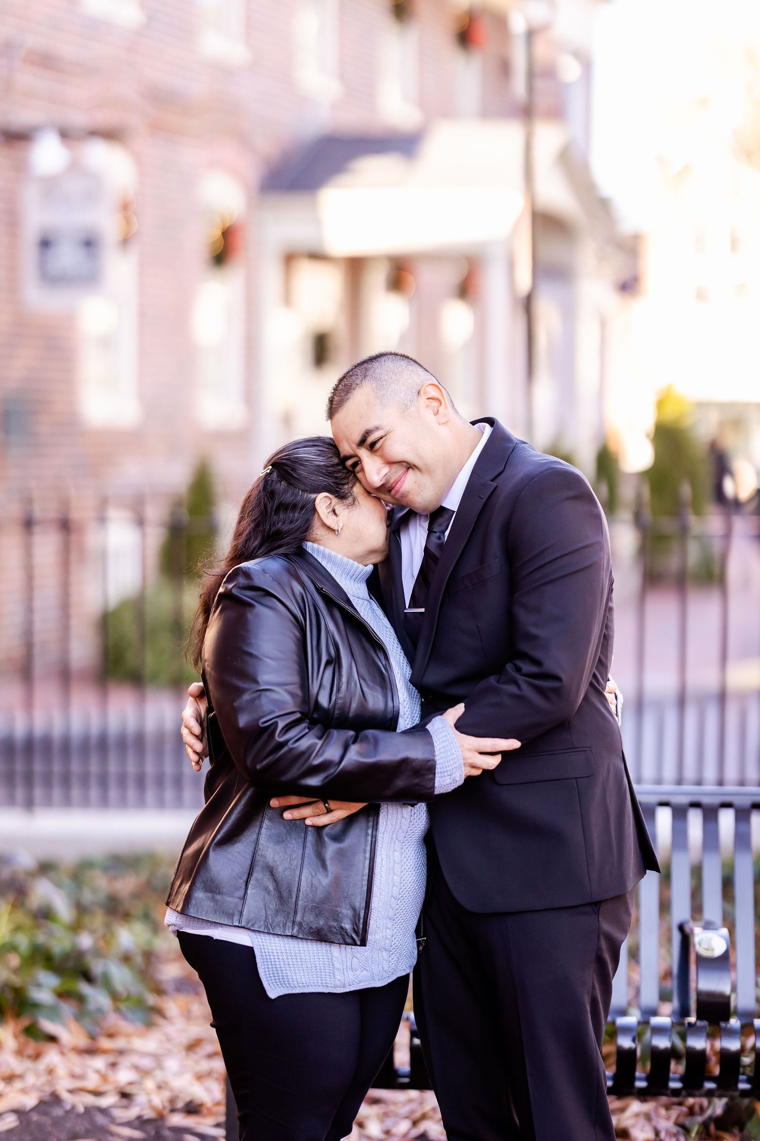 Intimate embrace between couple on brick path with building in background.