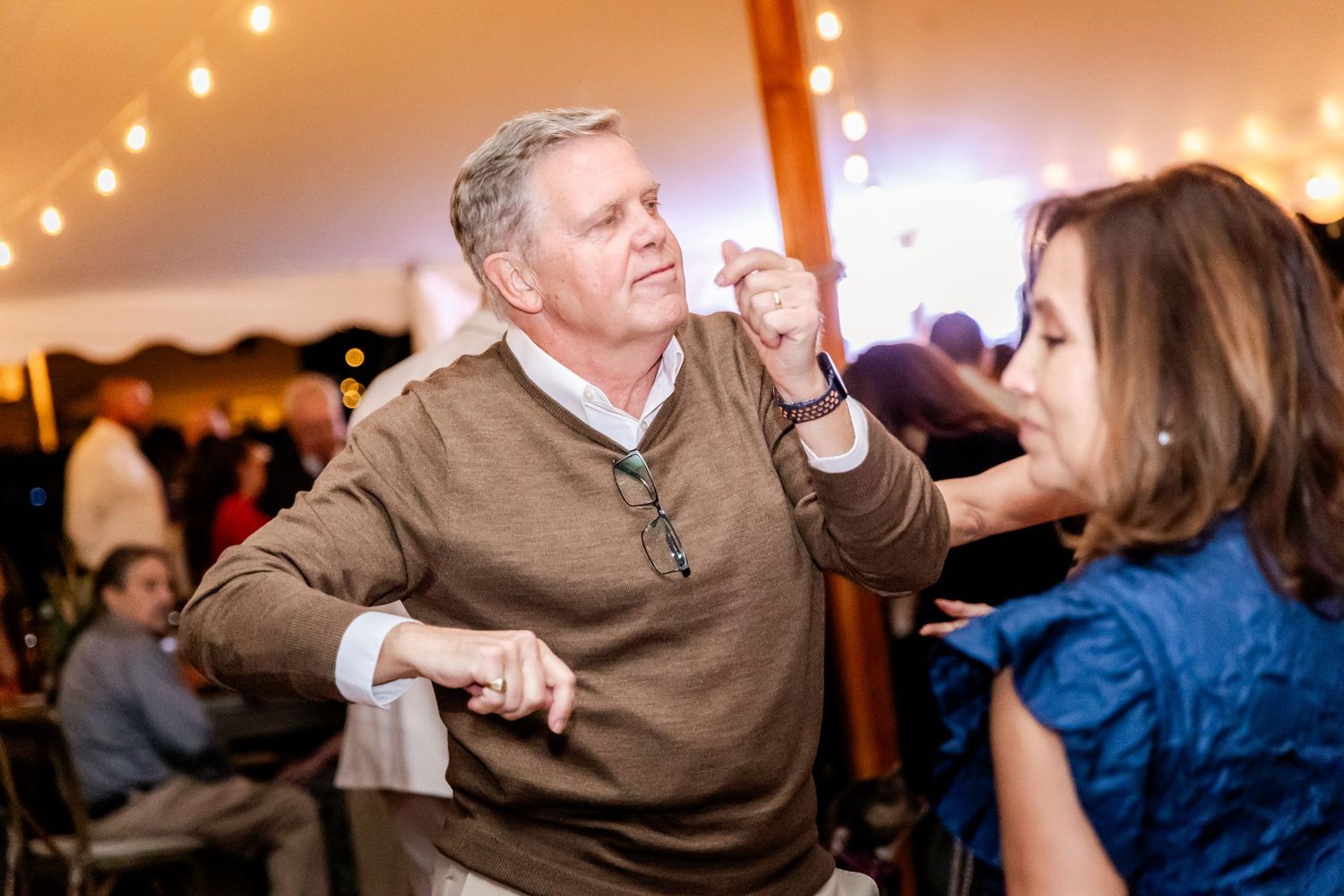 Wedding reception dance party with string lights creating a warm ambiance overhead.