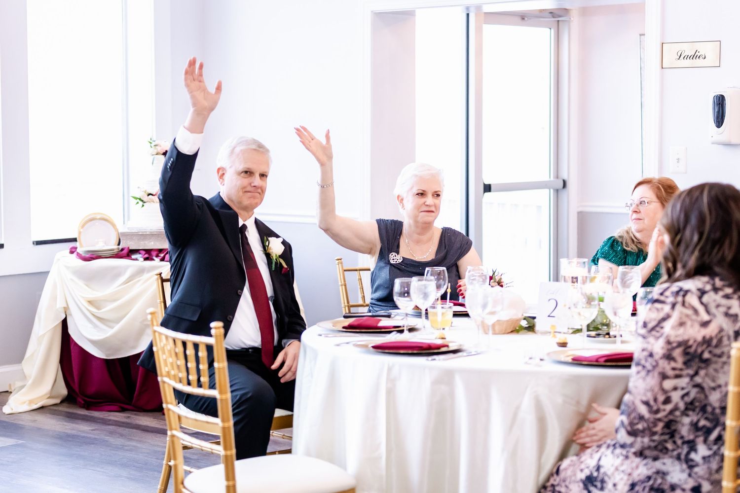 Wedding reception scene with guests celebrating at decorated tables.