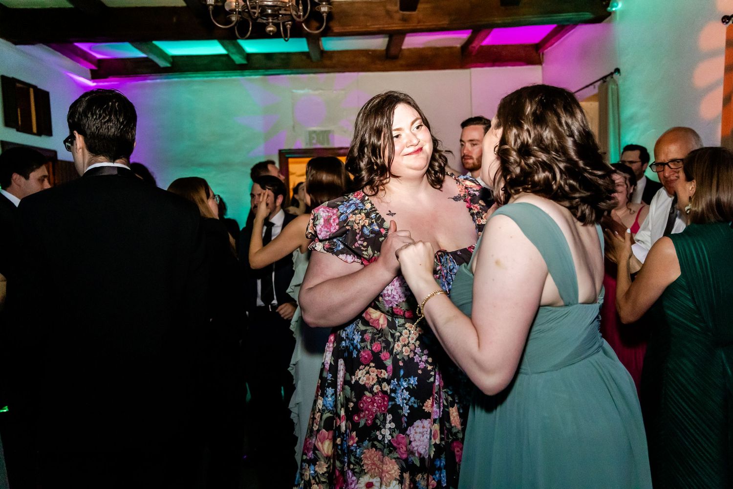 Guests dancing and celebrating at an evening wedding reception with colorful lighting.