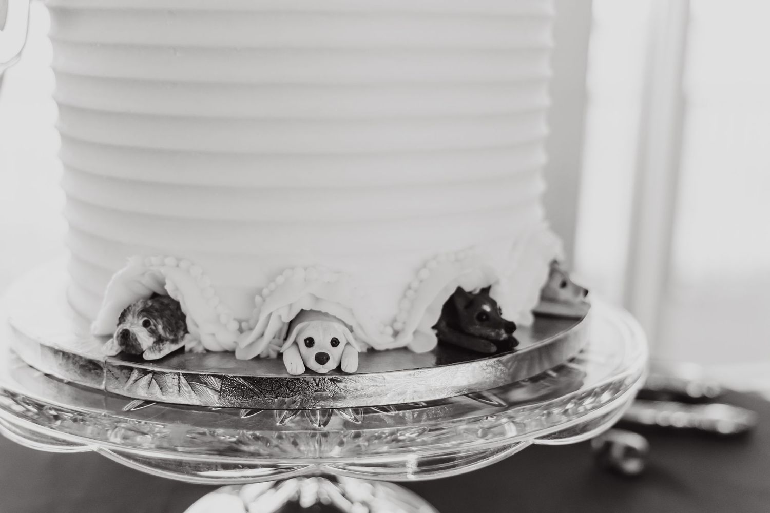 Black and white close-up of wedding cake decorations featuring tiny animal figurines.
