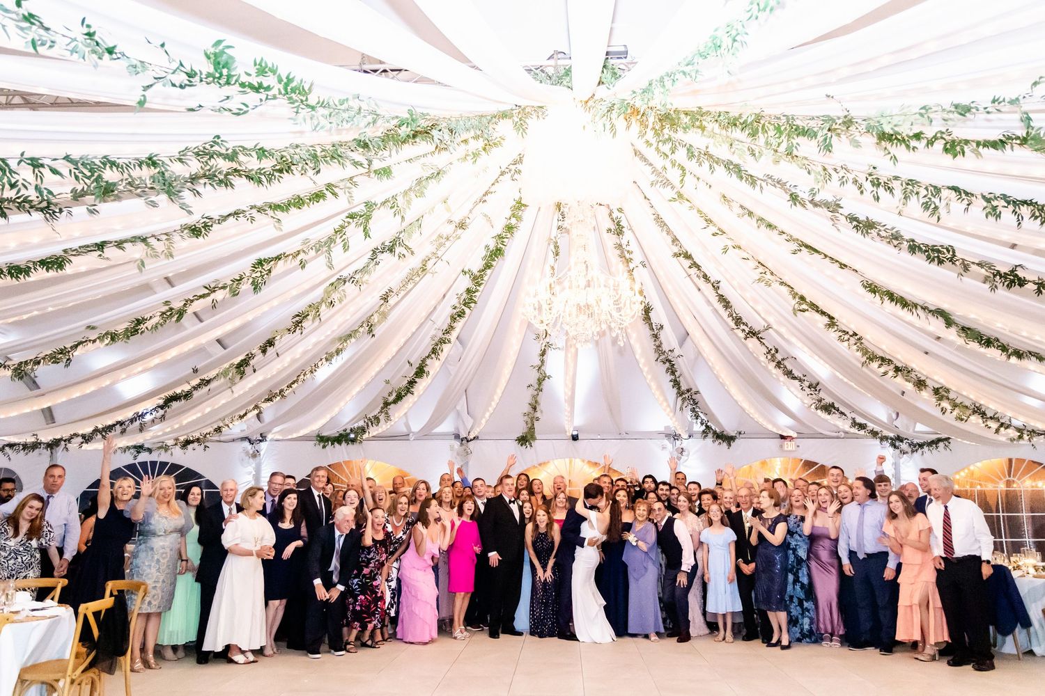 Elegant wedding reception setup with draped fabric ceiling and string lights creating a magical atmosphere.