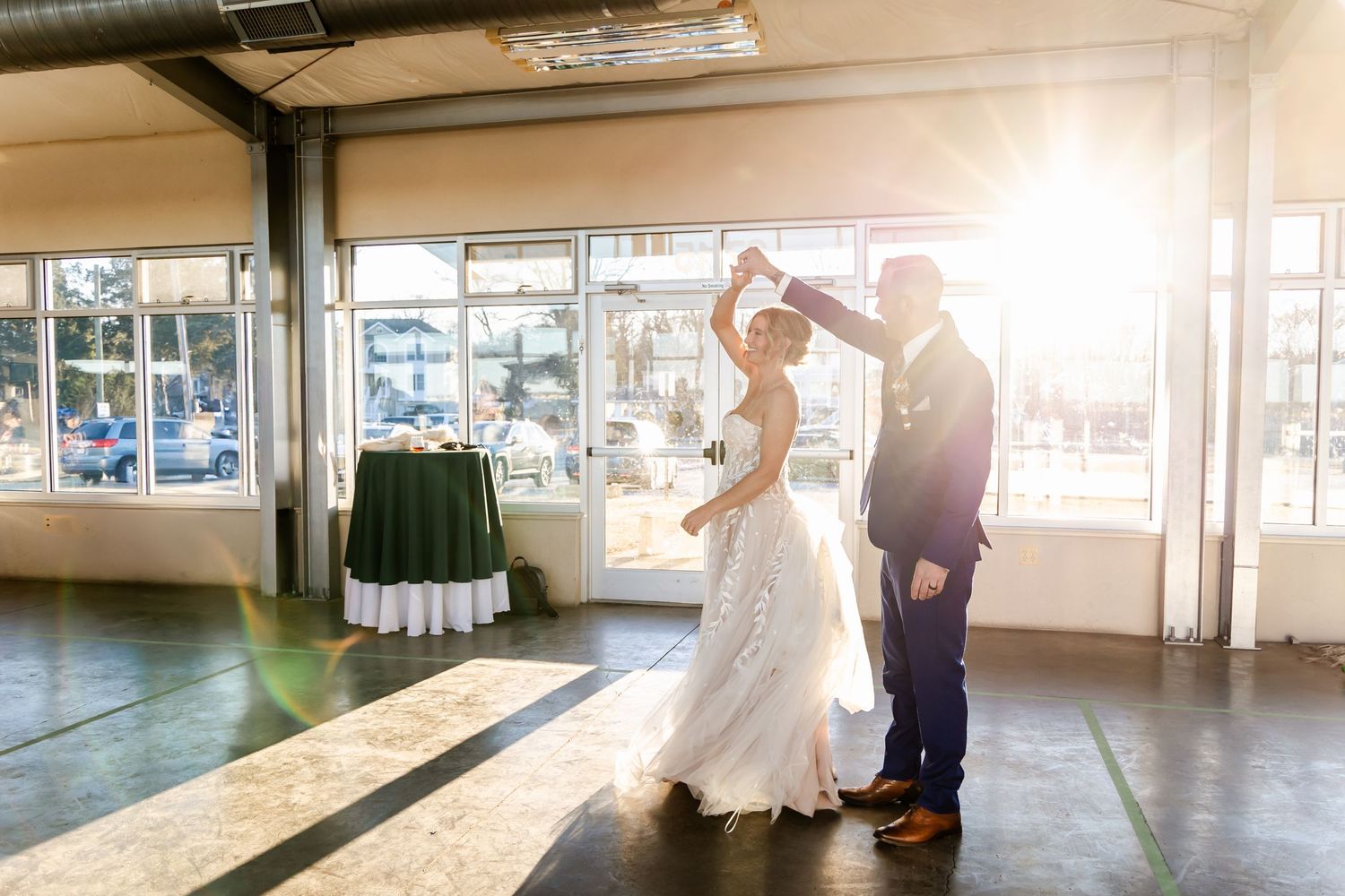 A couple shares their first dance in a sunlit industrial wedding venue.