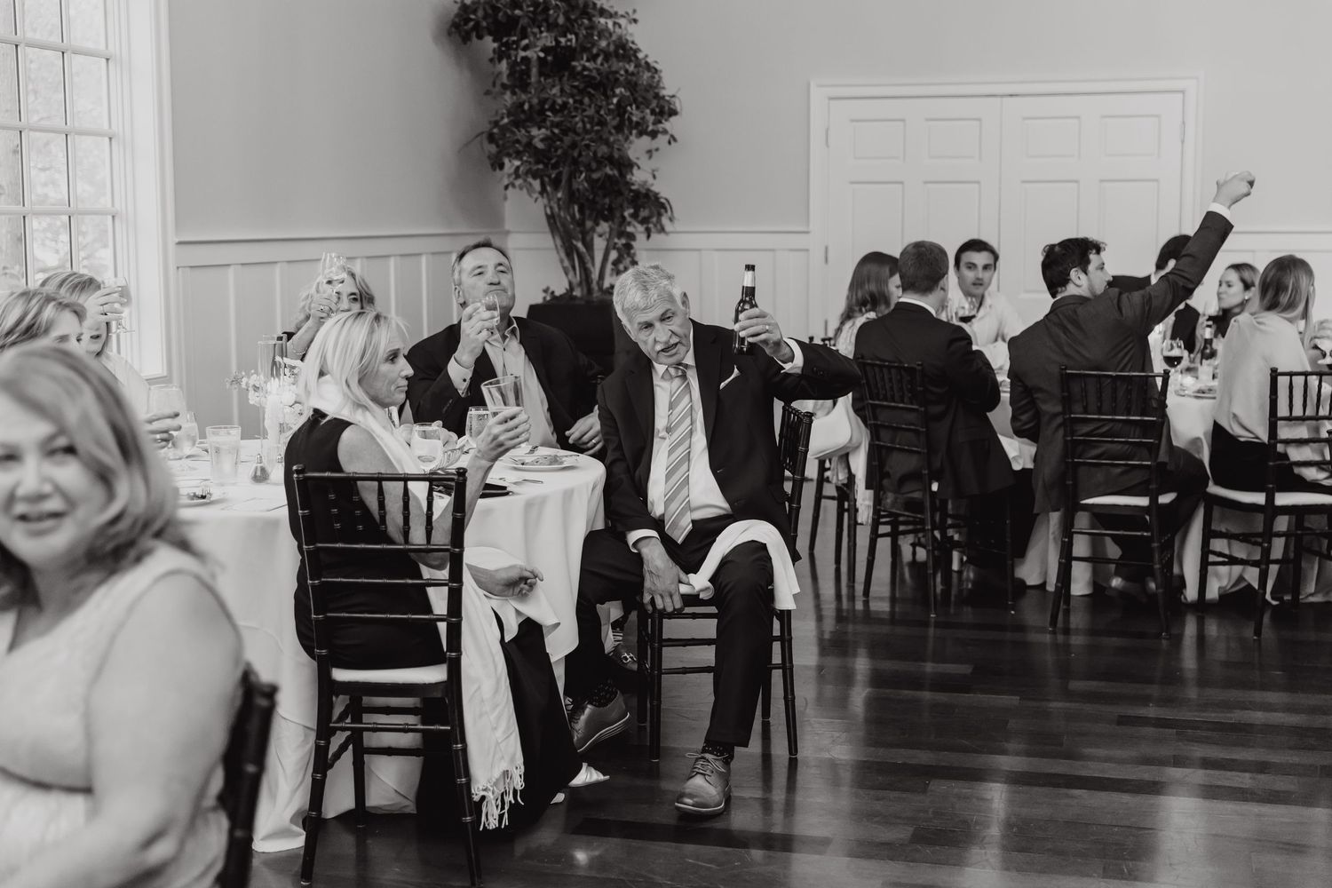 Black and white photo of wedding guests seated at tables during reception.