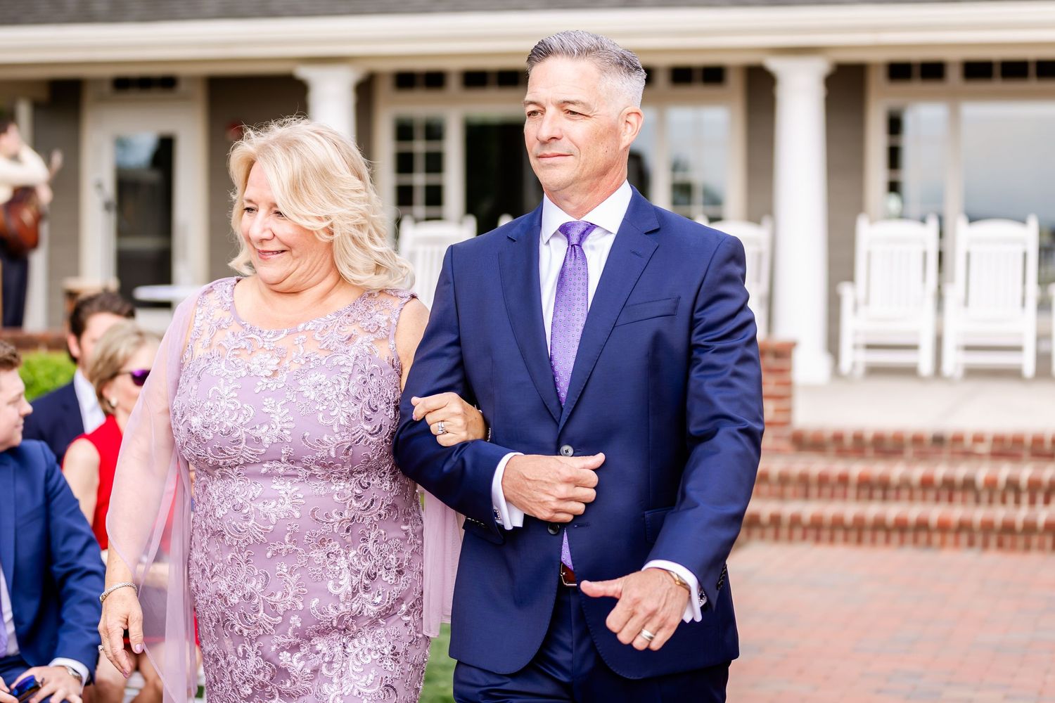 Wedding celebration with guests in formal attire outside a traditional brick building.
