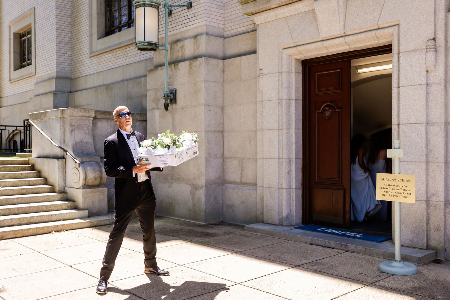 A person in a suit walks up stone steps at the entrance of a grand government or institutional building entrance.