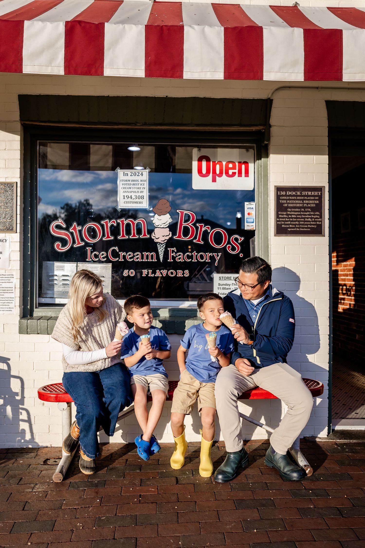 Family enjoying ice cream together outside Storm Bros Ice Cream Factory on a sunny day.