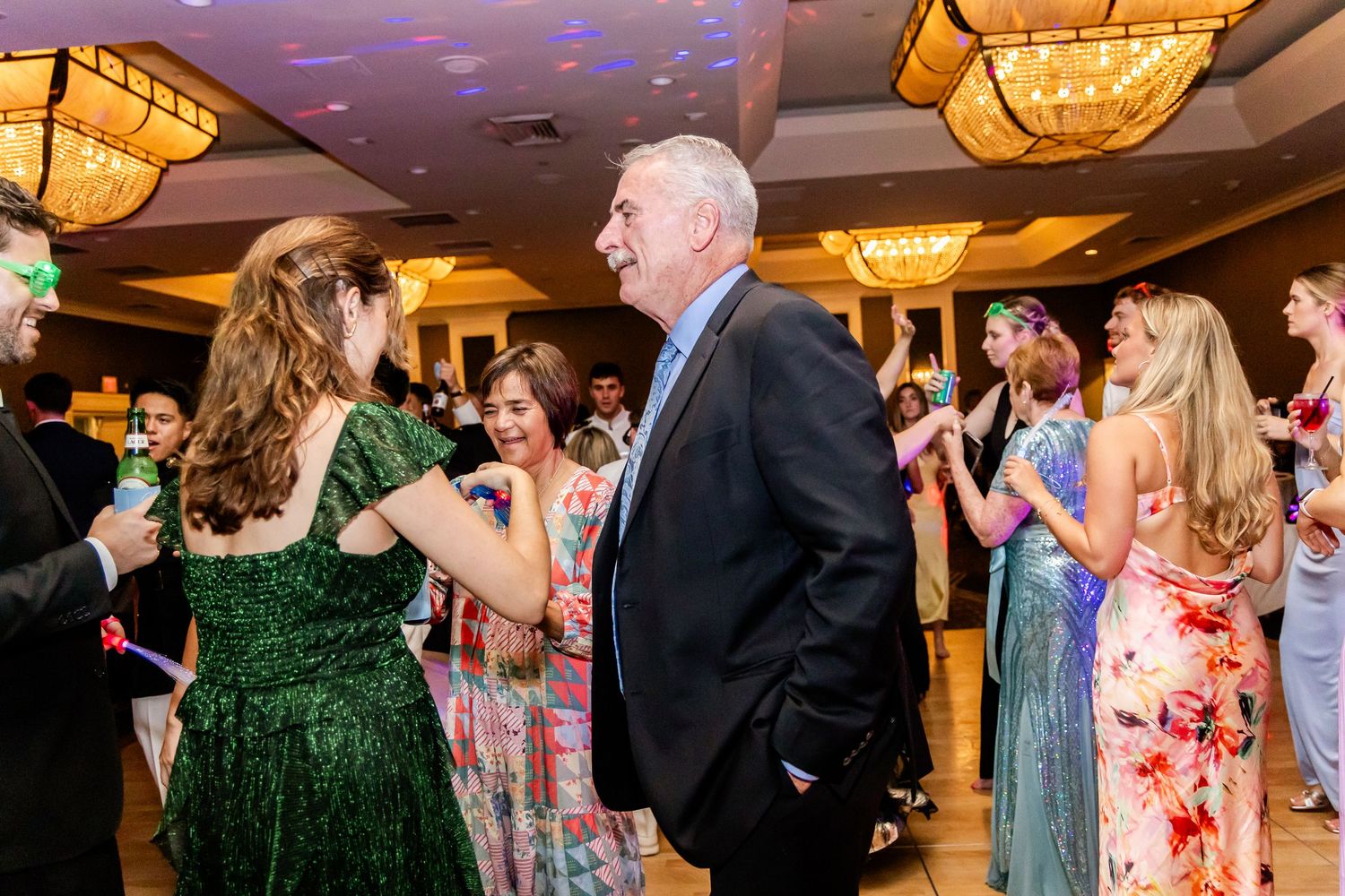 Reception party with colorful disco lights and guests dancing on the dance floor.