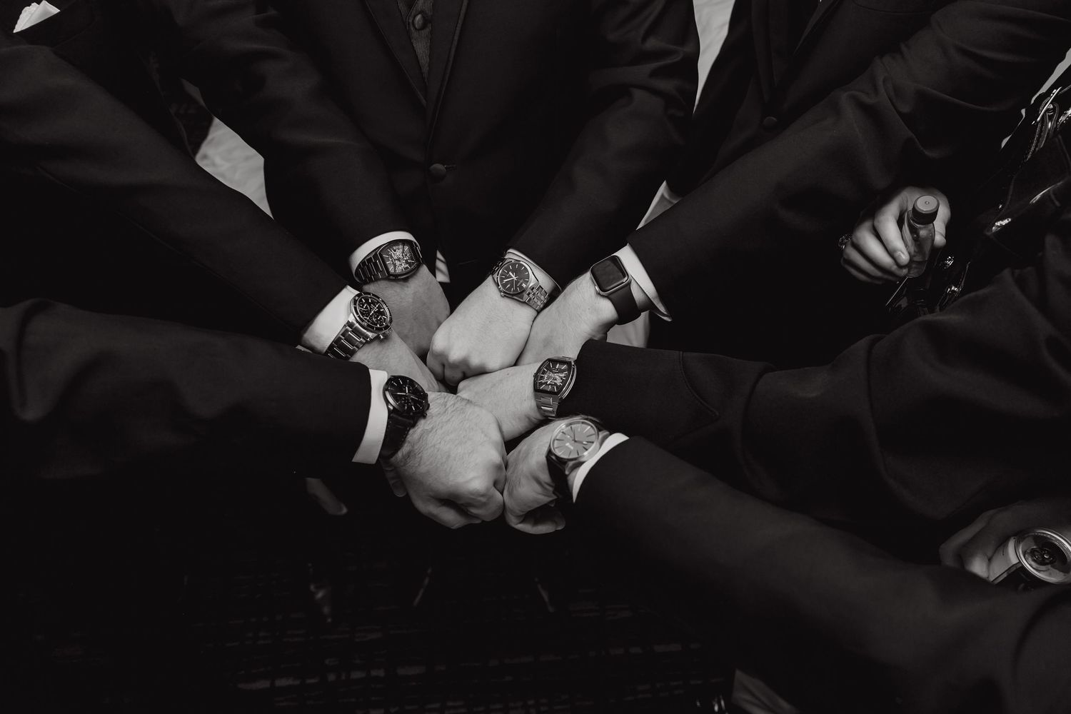 Formal black suits and hands shown during an elegant wedding ceremony.
