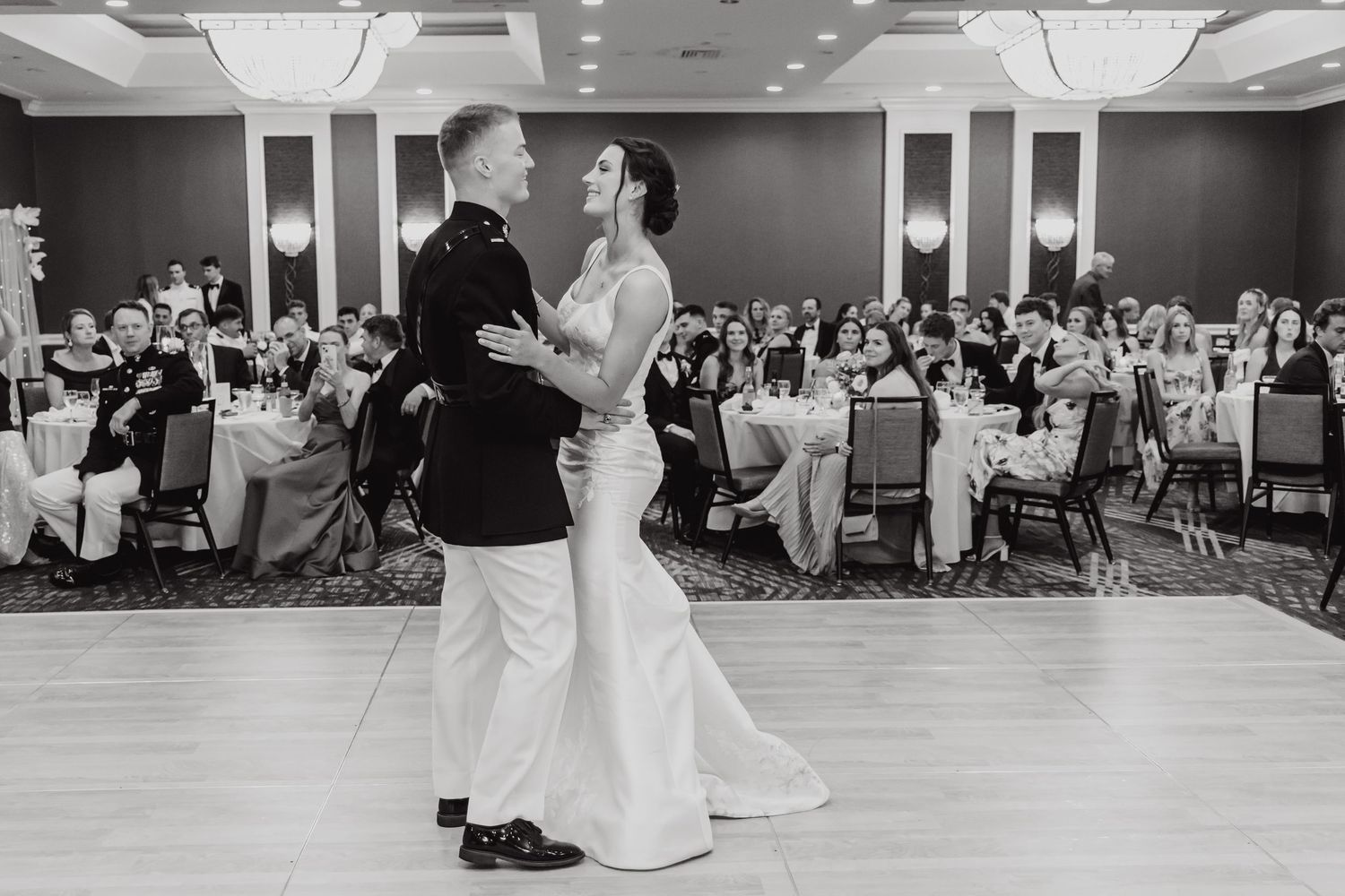 Couple shares first dance in elegant ballroom during wedding reception.