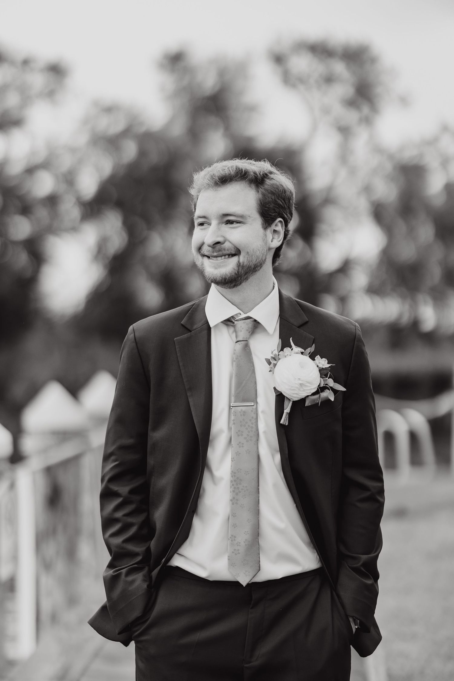 Black and white portrait shots of a groom in formal attire outdoors.