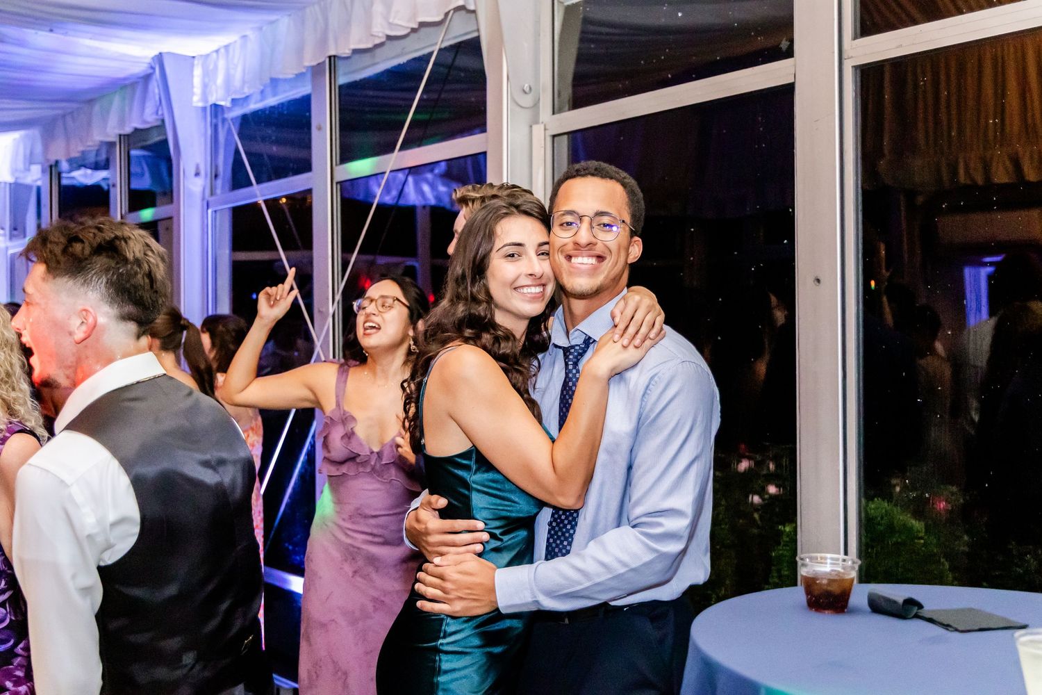 Couples dance together during evening wedding reception with blue accent lighting.