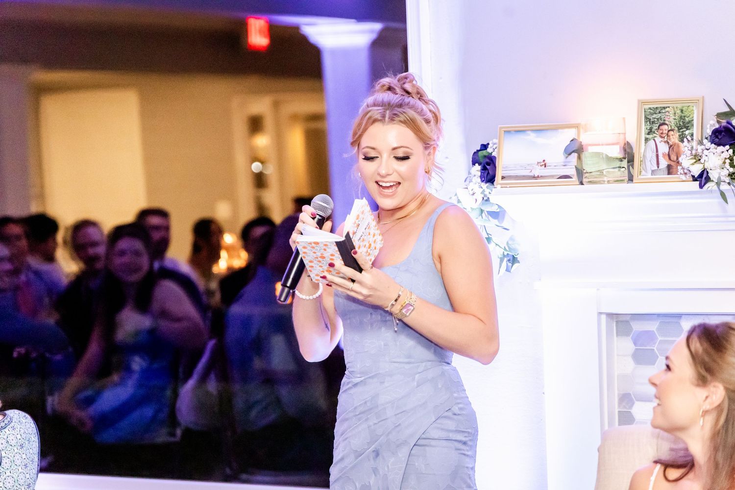 A bridesmaid in a gray dress checks her phone during the wedding reception.