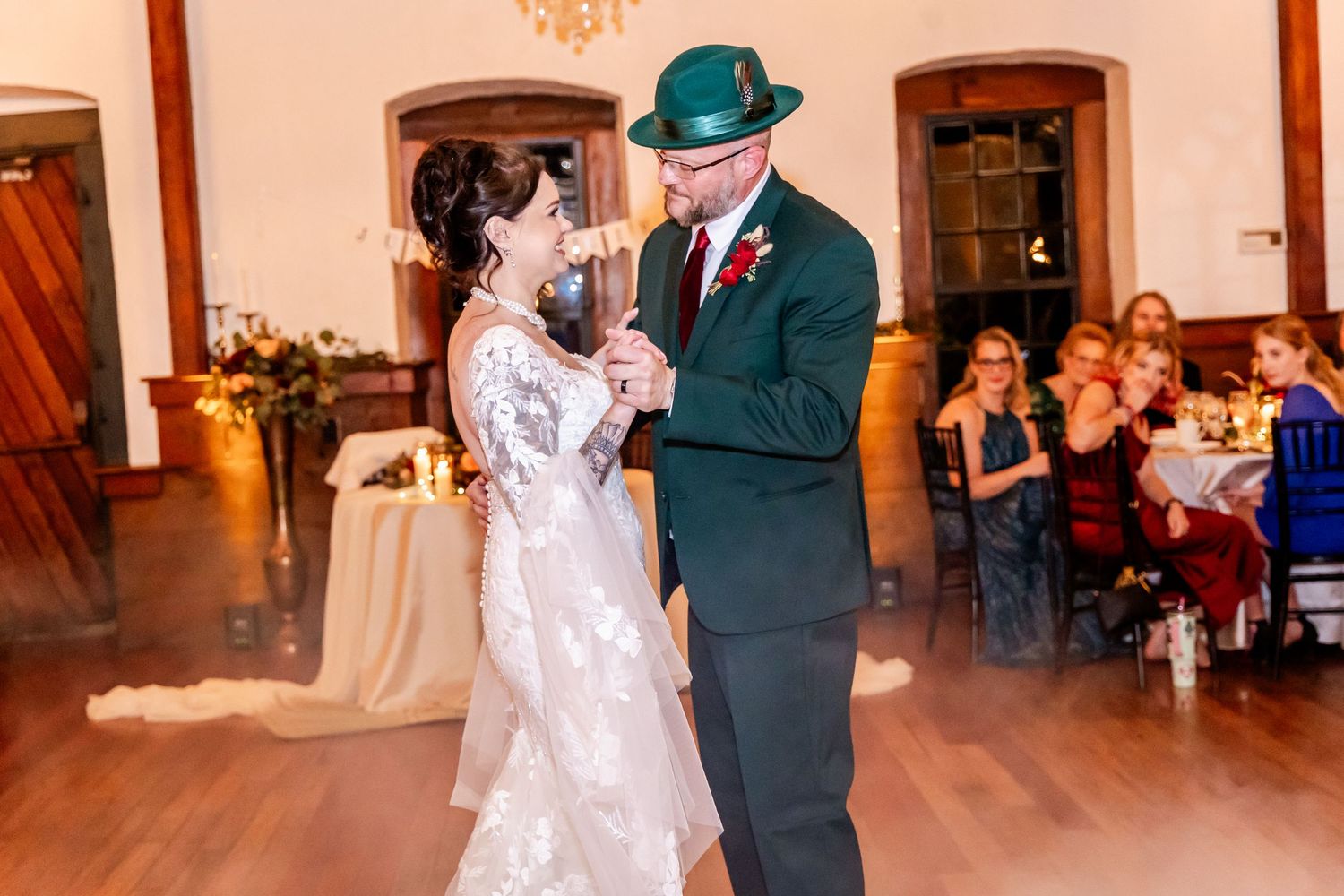 Couple sharing a dance on hardwood floor during wedding reception in elegant venue.