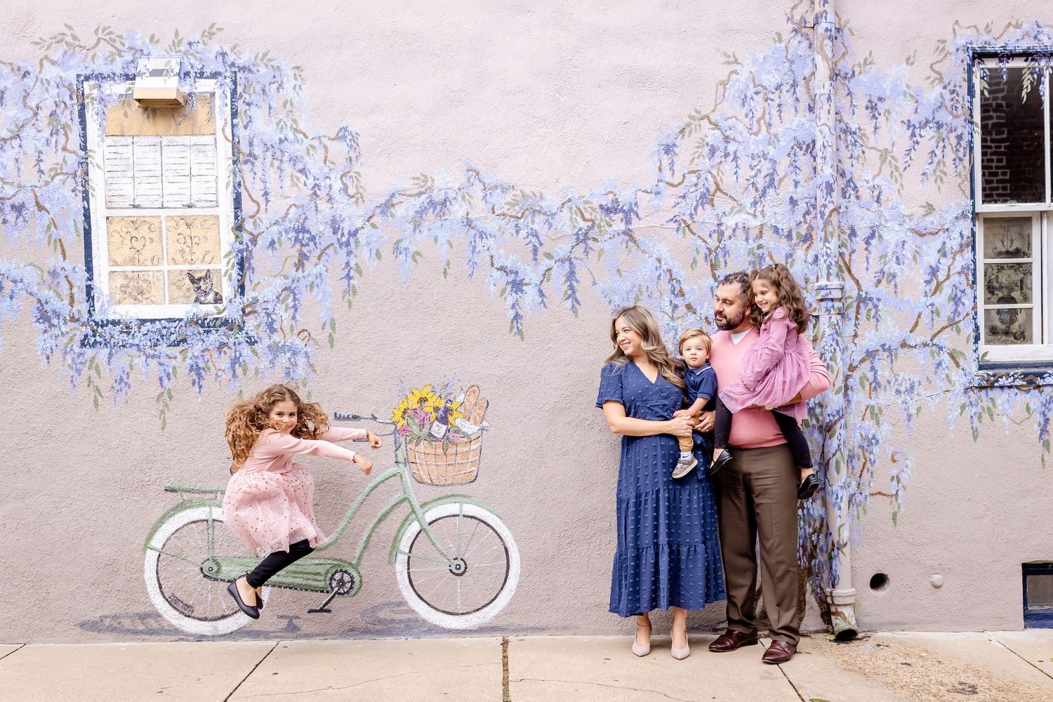 A sequence of five photos showing people posing with a white bicycle against a blue and white textured wall.