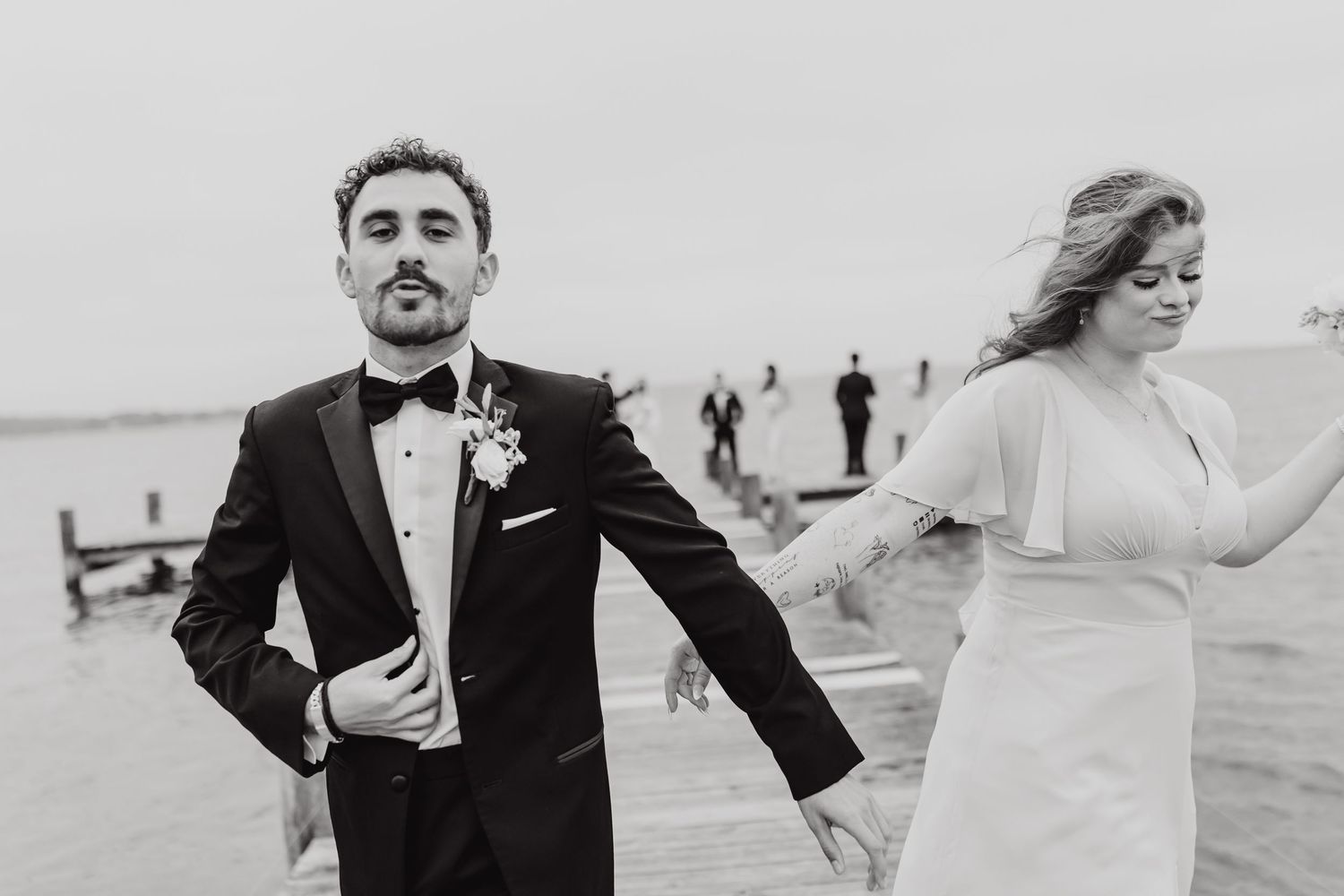 A couple in formal wedding attire shares a romantic moment on a beach at sunset.