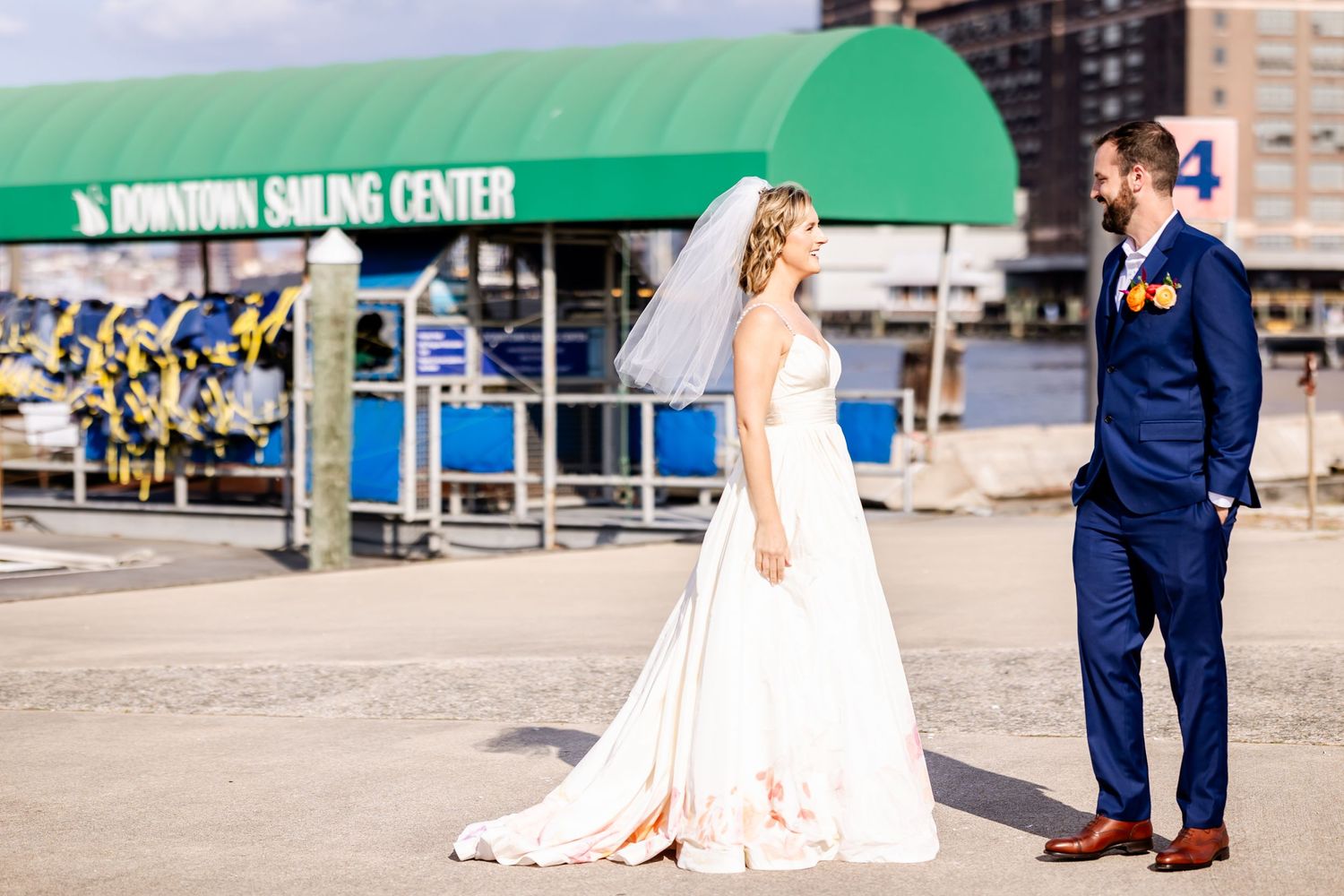 A bride and groom stand together at a waterfront dock on their wedding day.