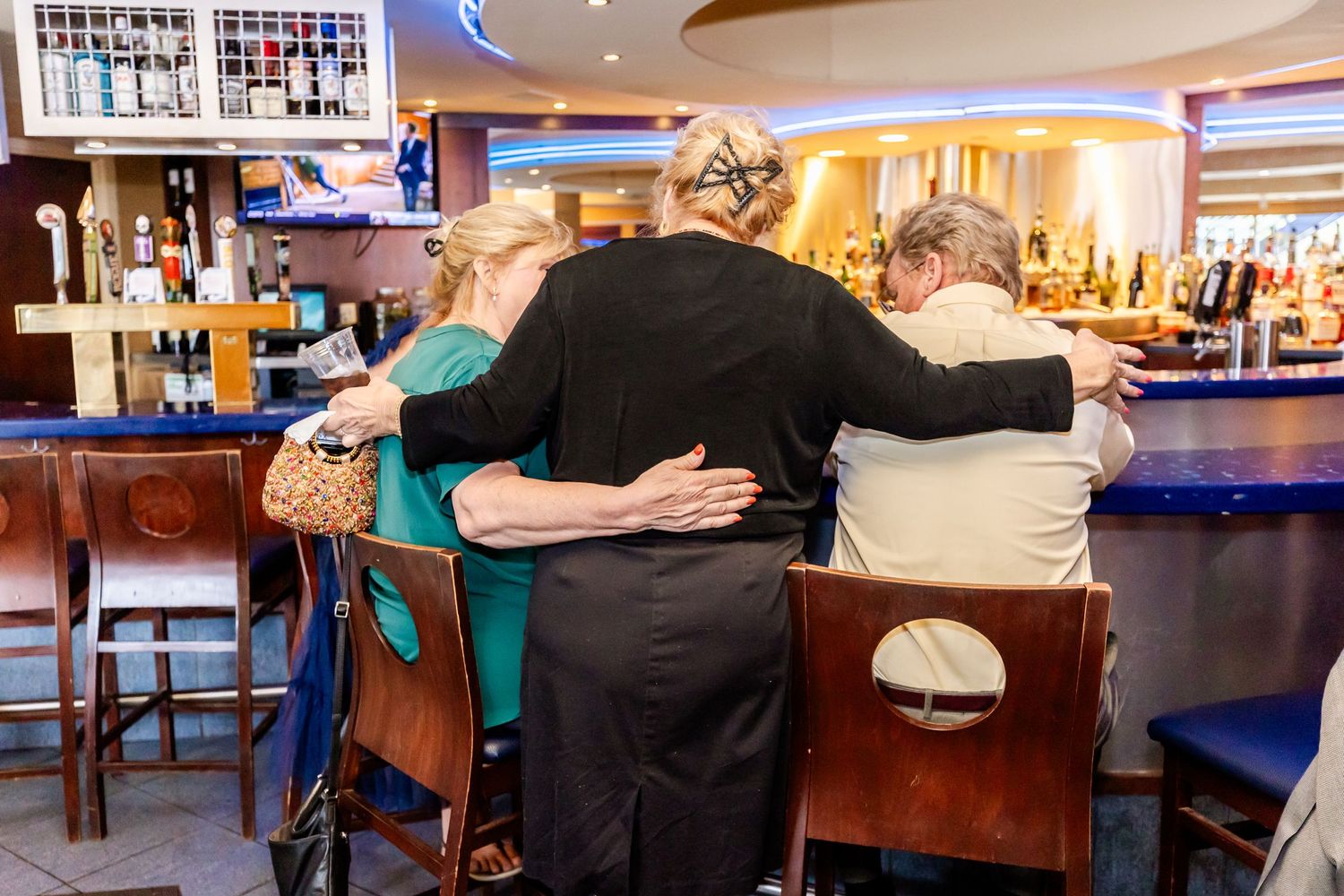 Group of people embracing in a heartfelt moment at a bar counter.