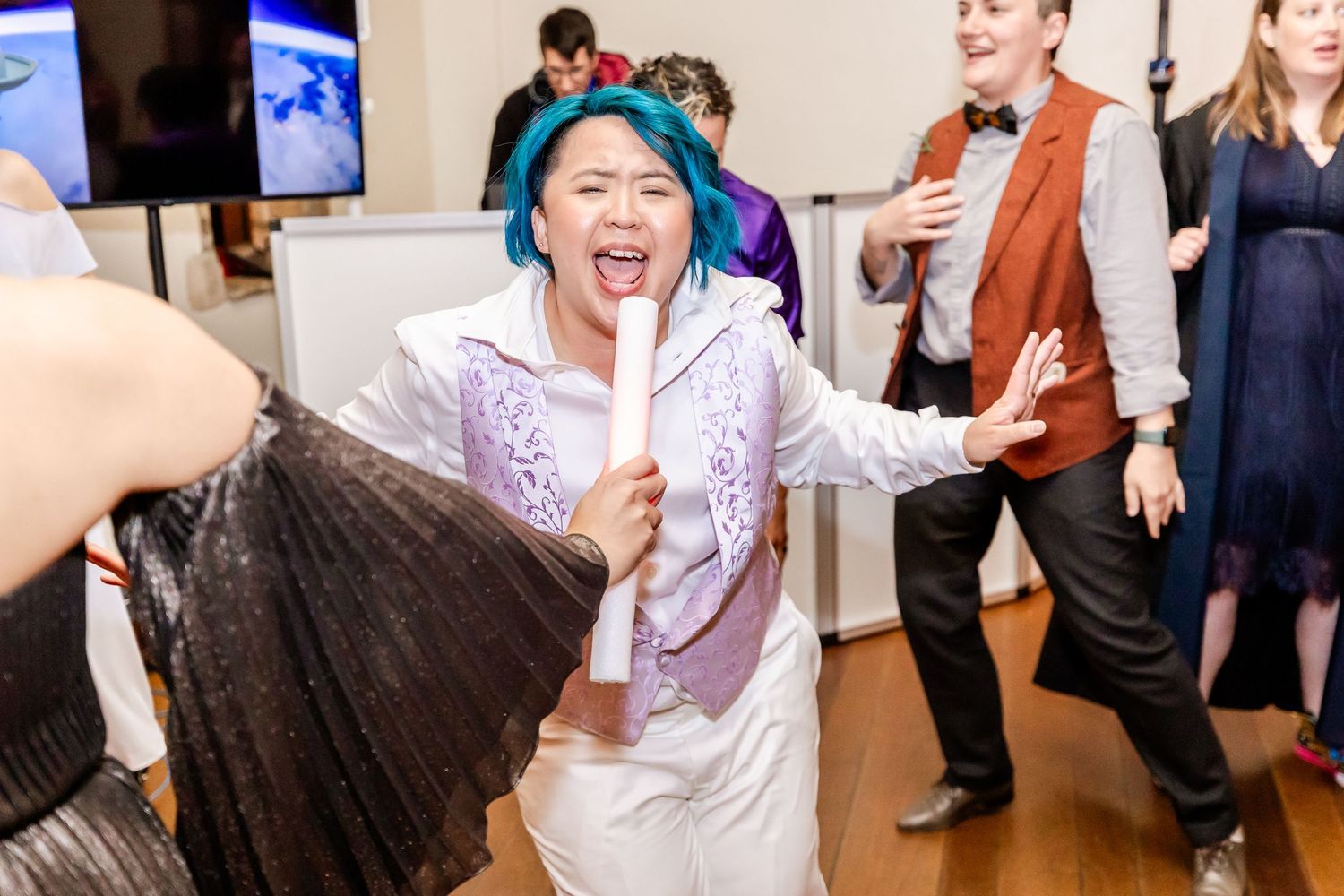 Guests dancing enthusiastically at an indoor party with colorful outfits and energetic movements.