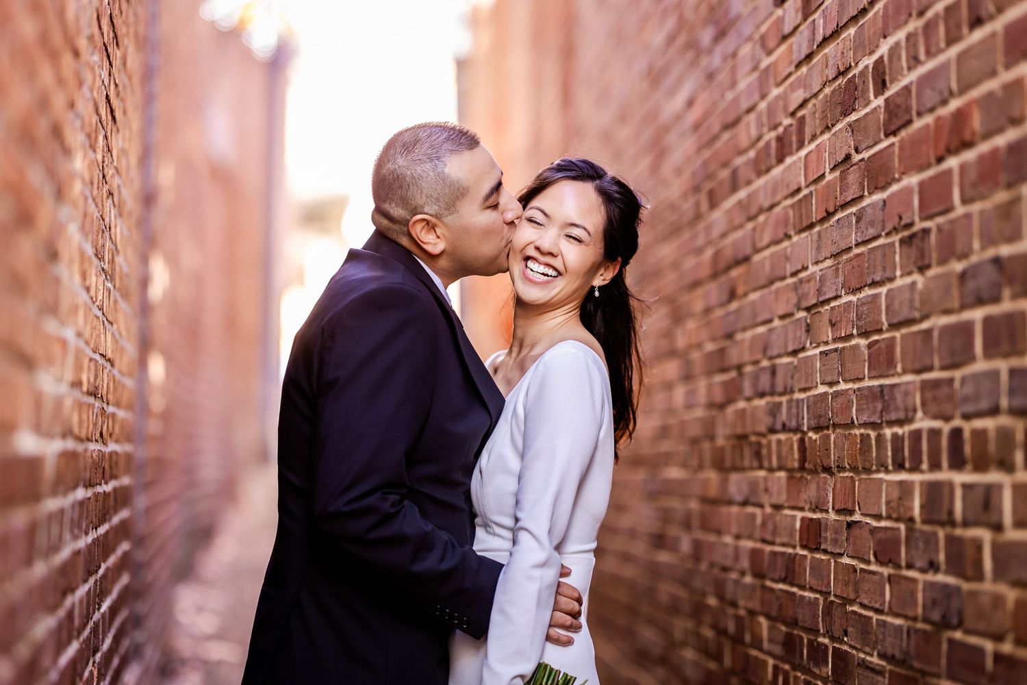 Romantic moment between newlyweds in an urban alley with brick walls.