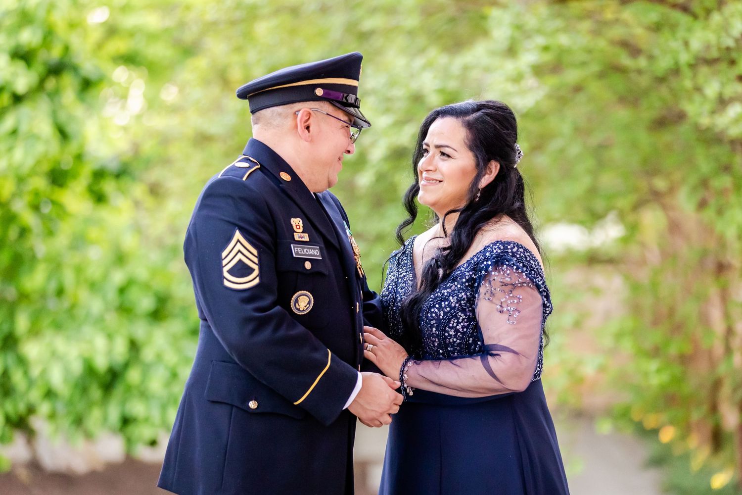 A military servicemember and companion share an intimate moment outdoors in formal attire.