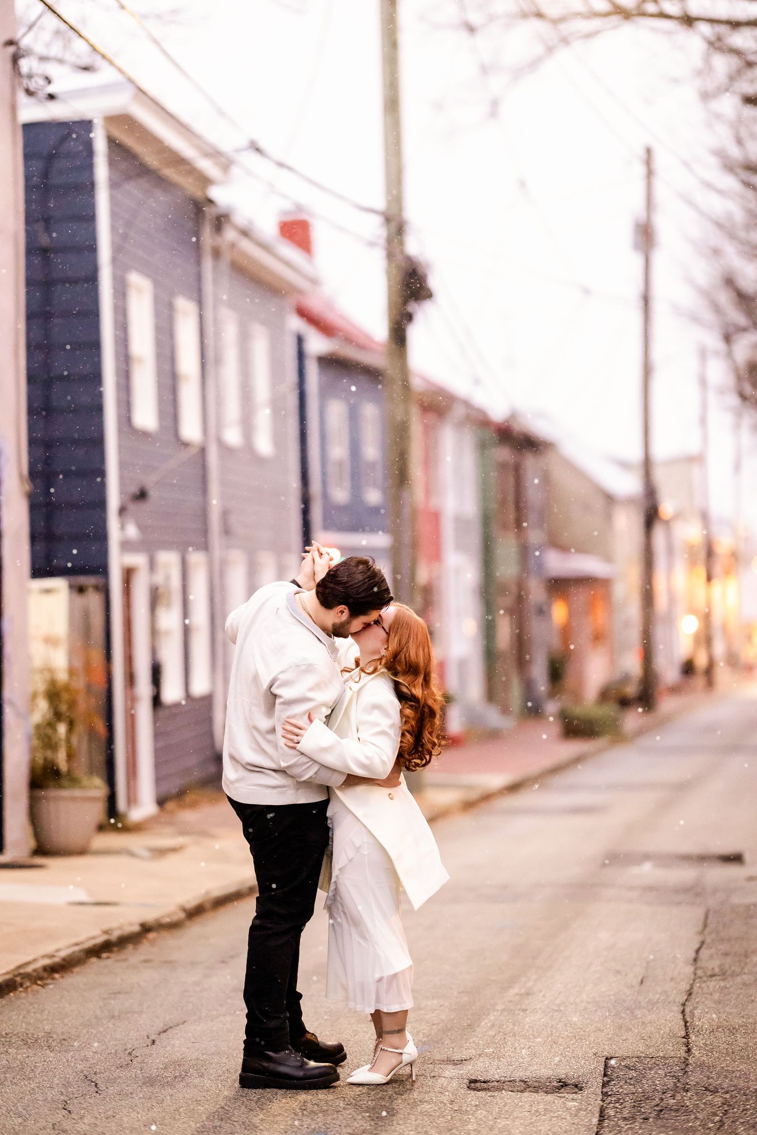 A couple in wedding attire shares a romantic moment on an empty city street at dusk.