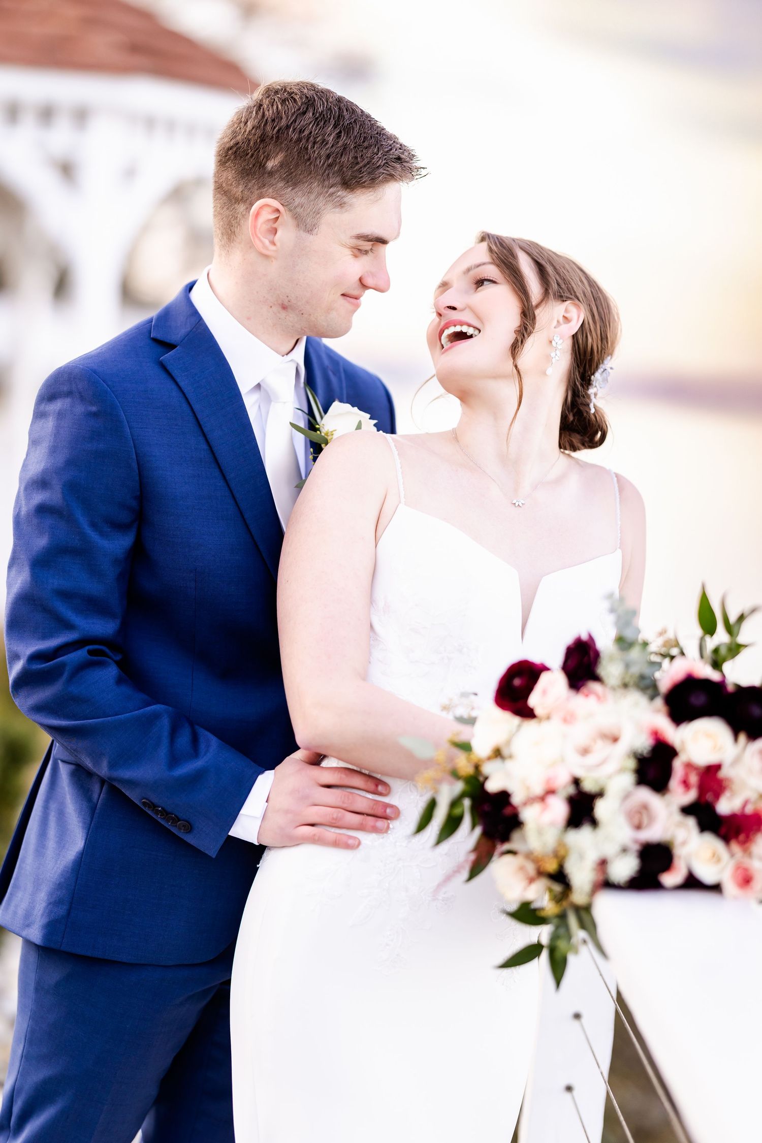 A couple in wedding attire share an intimate moment with a floral arrangement in soft lighting.
