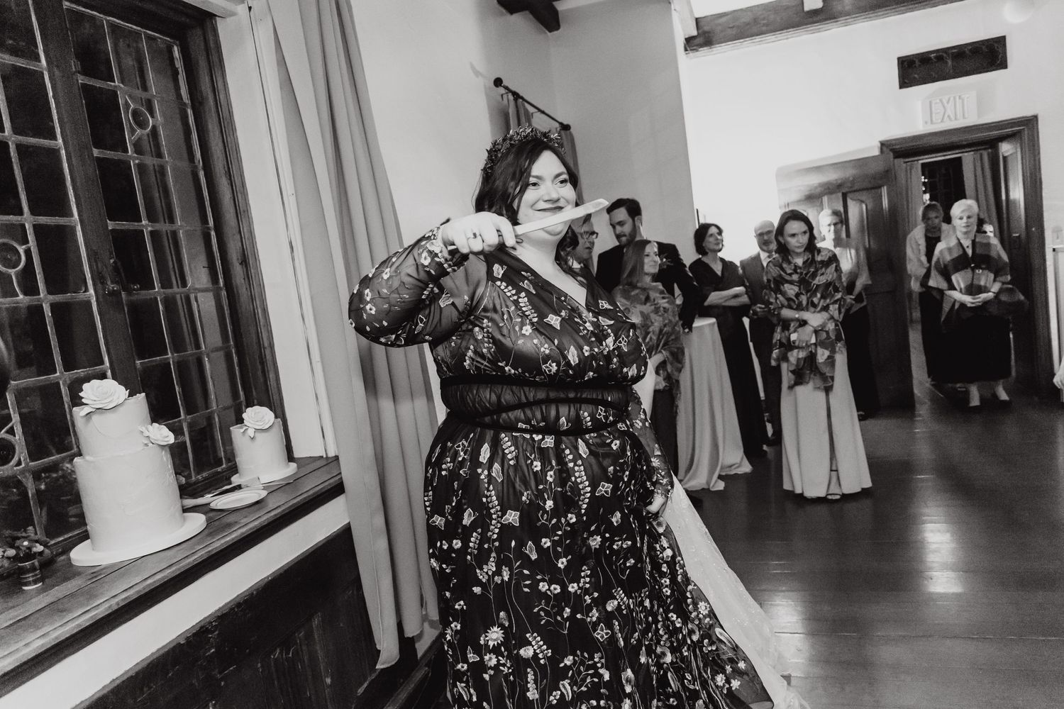 Black and white photo of wedding guest dancing energetically in a floral dress.