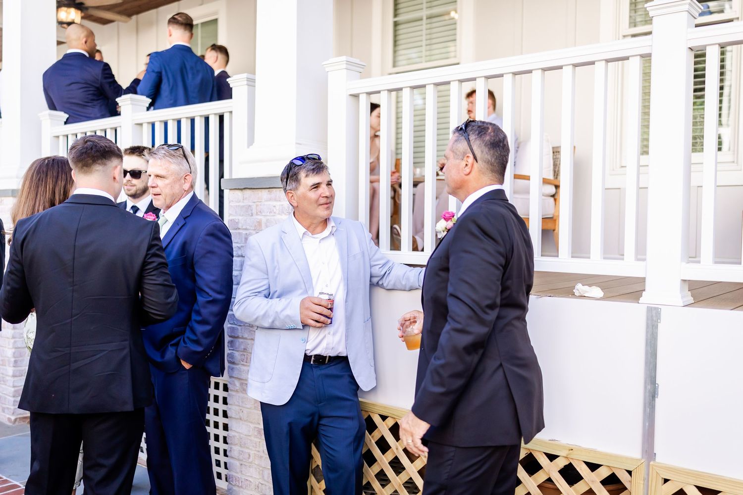 Guests in formal attire socializing on a white columned porch.