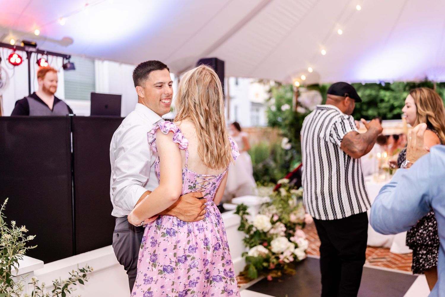 Couples dance together at an elegant wedding reception decorated with floral arrangements and soft lighting.