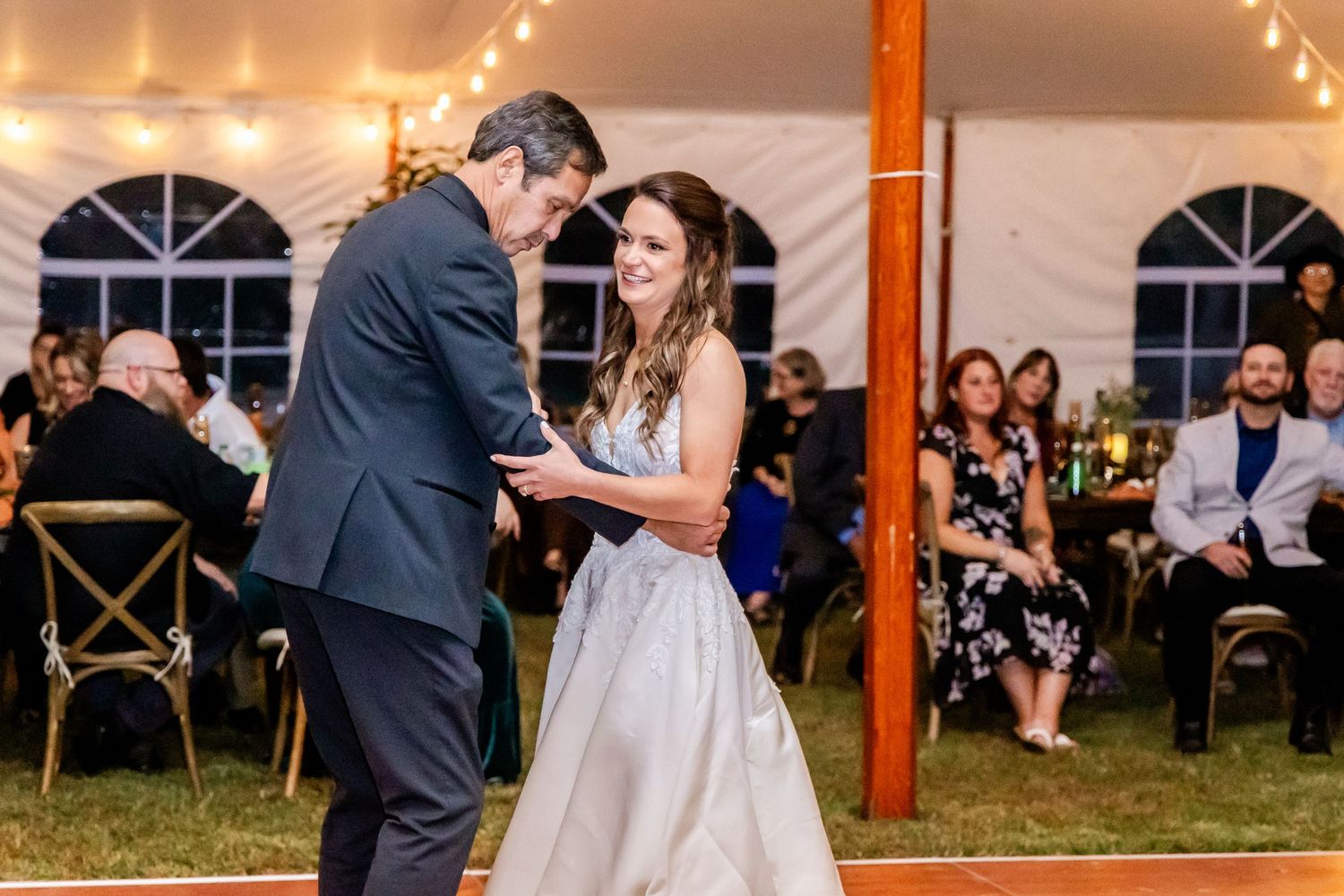 Wedding reception under a tent with string lights creating a warm ambiance.