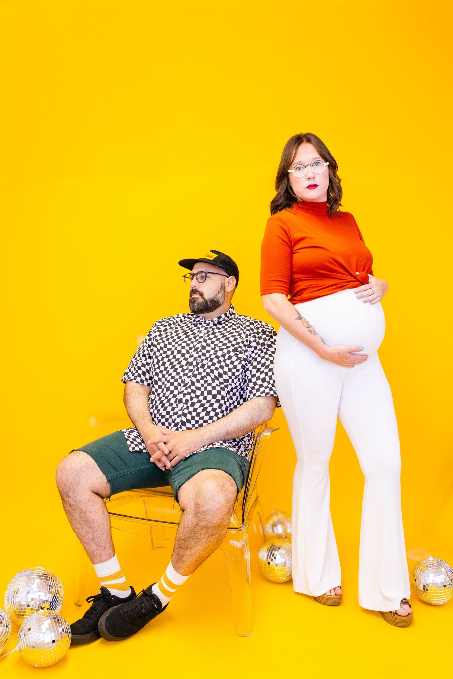 Person in checkered shirt and green shorts sitting on yellow background with white pants visible in frame.
