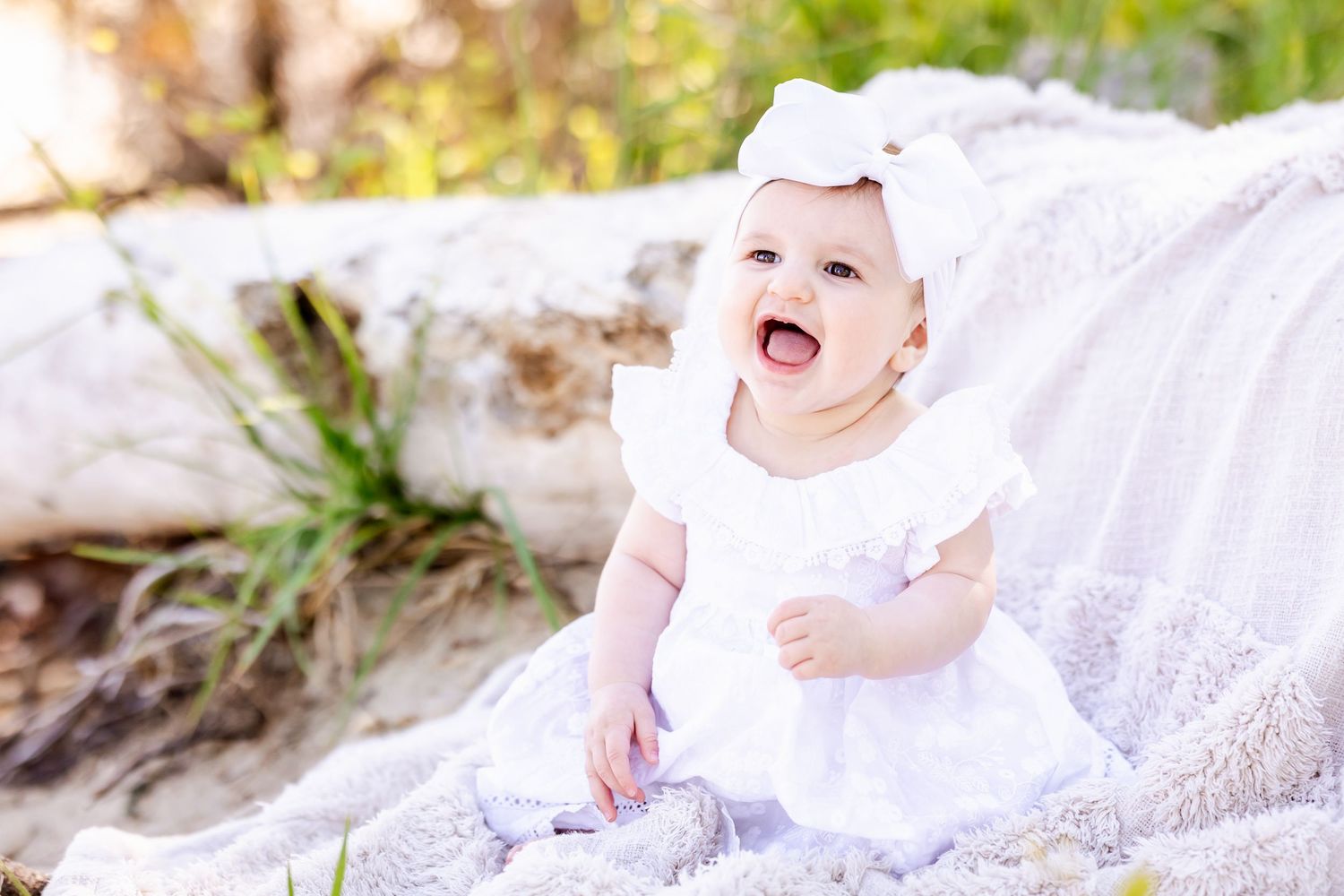 A joyful moment captured in white attire against a natural outdoor backdrop with sunlit foliage.