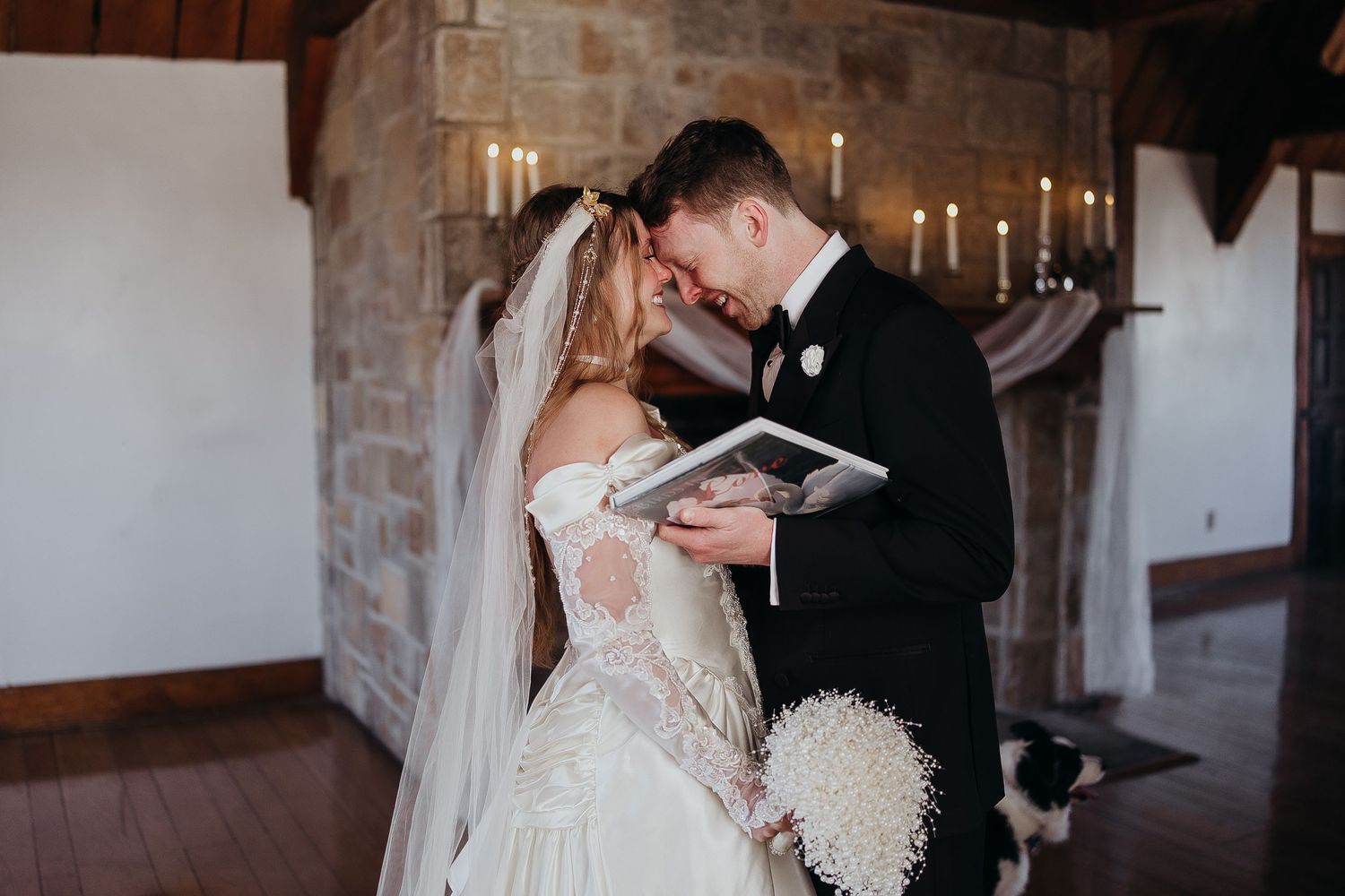 Bride and groom share intimate moment reading vows in rustic stone venue with candlelit backdrop.
