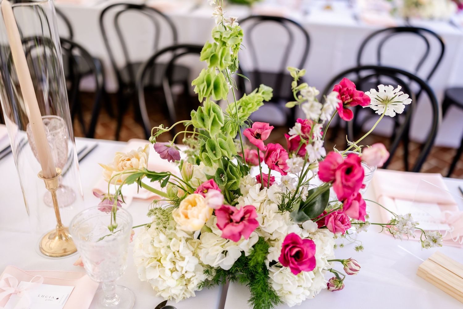 Wedding reception table decorated with pink and white floral centerpieces and elegant place settings.