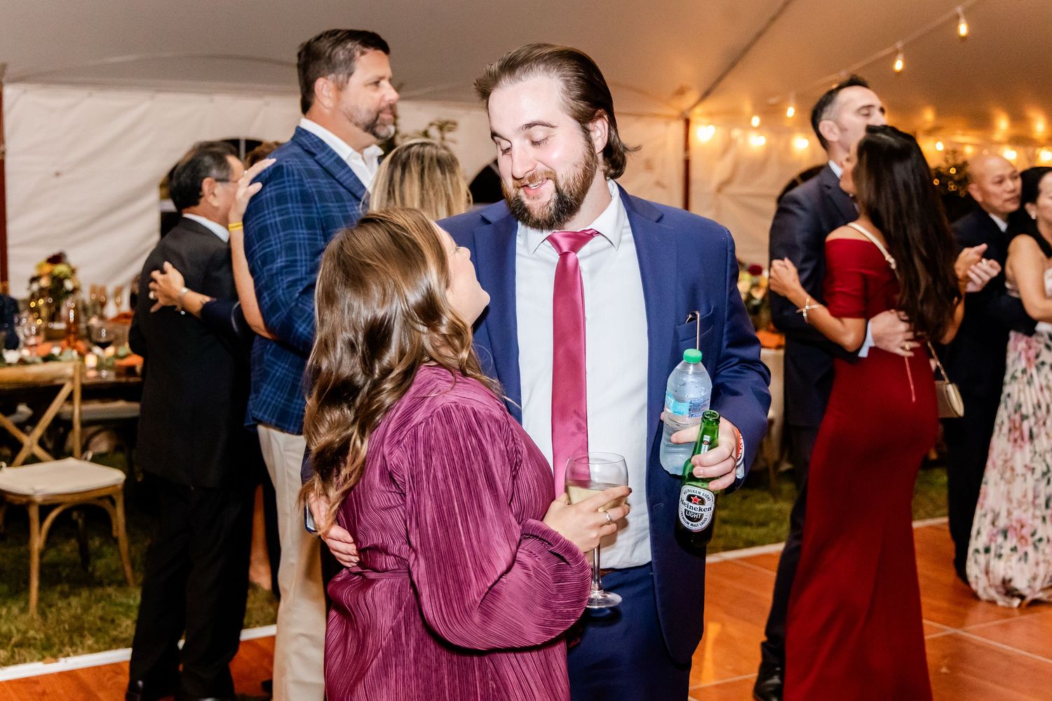 Wedding guests dancing and celebrating at a reception under string lights.