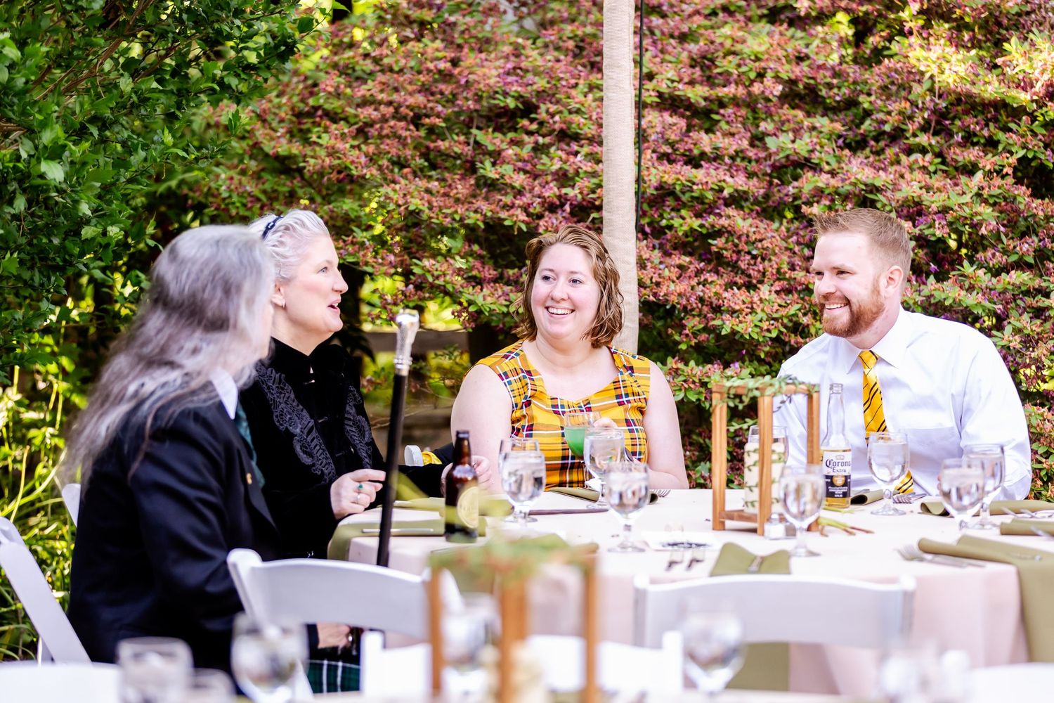 Wedding guests enjoying conversation and drinks at an outdoor reception table.