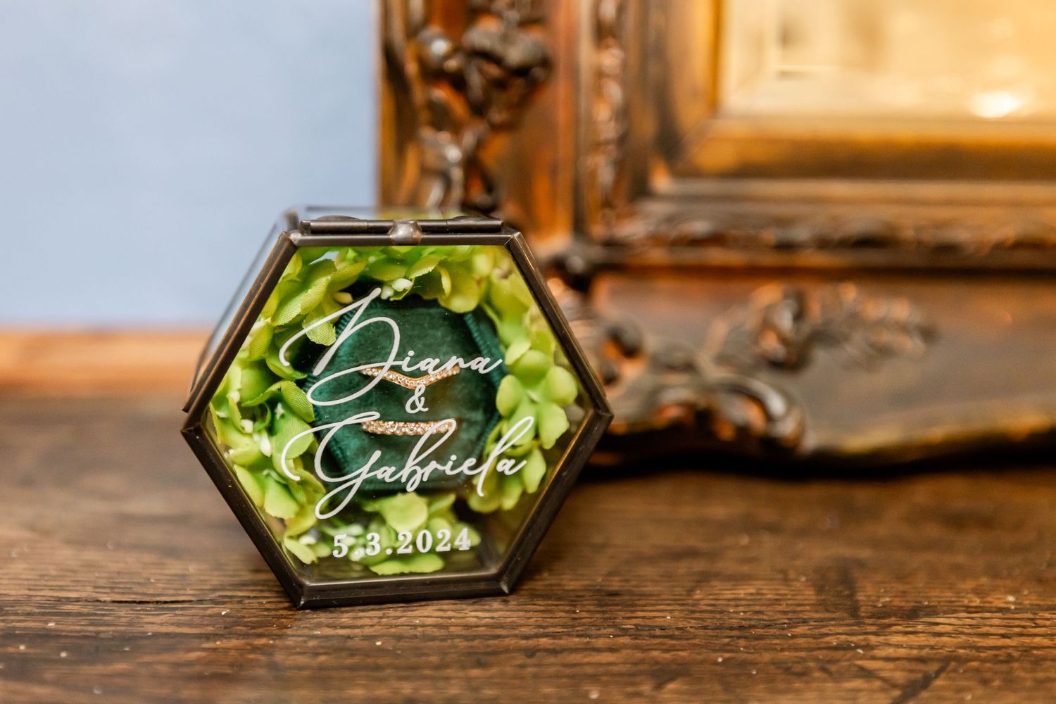 A decorative hexagonal glass box with elegant calligraphy sits on a wooden surface.