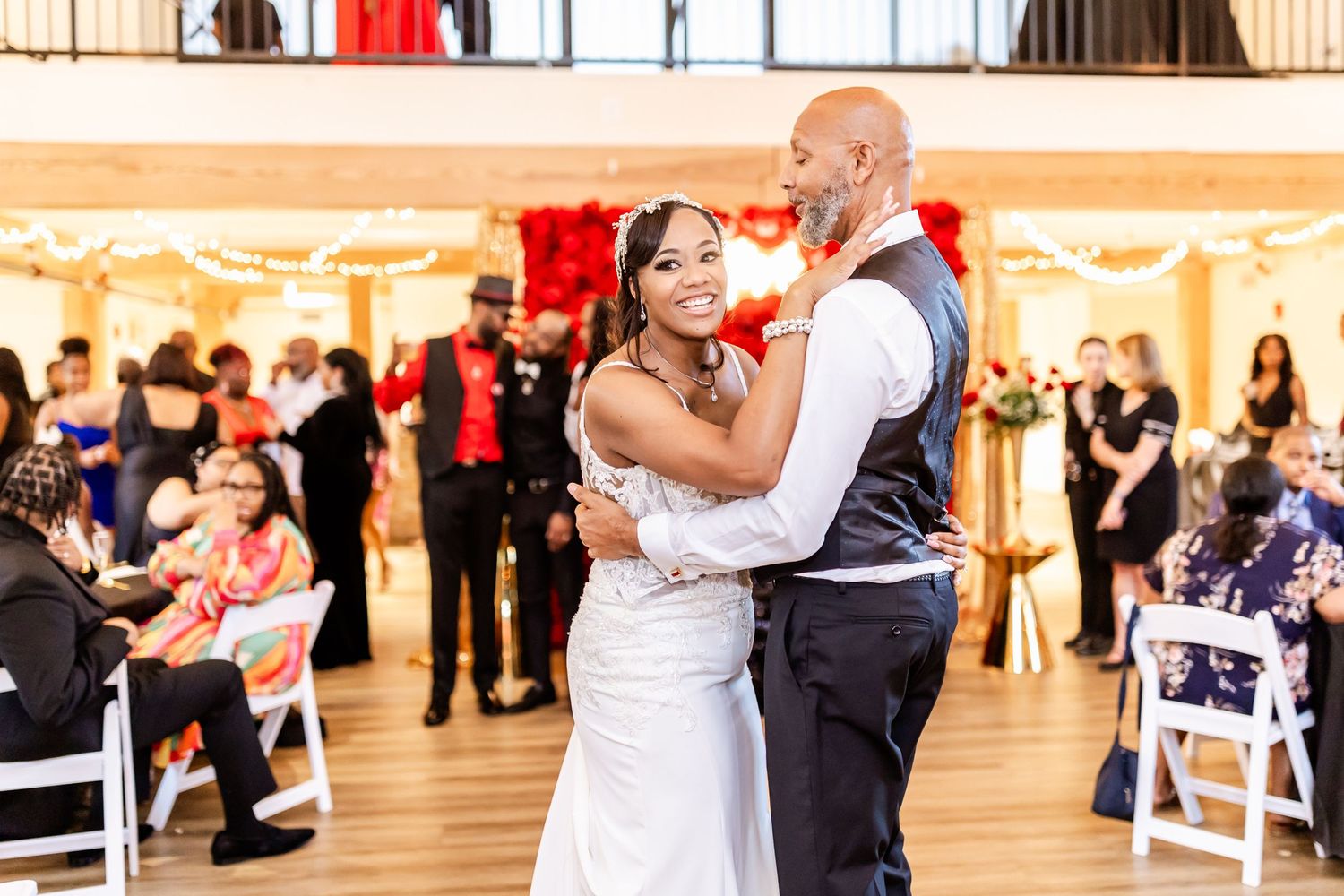 Wedding reception dance in an elegant venue with balcony and hardwood floors.