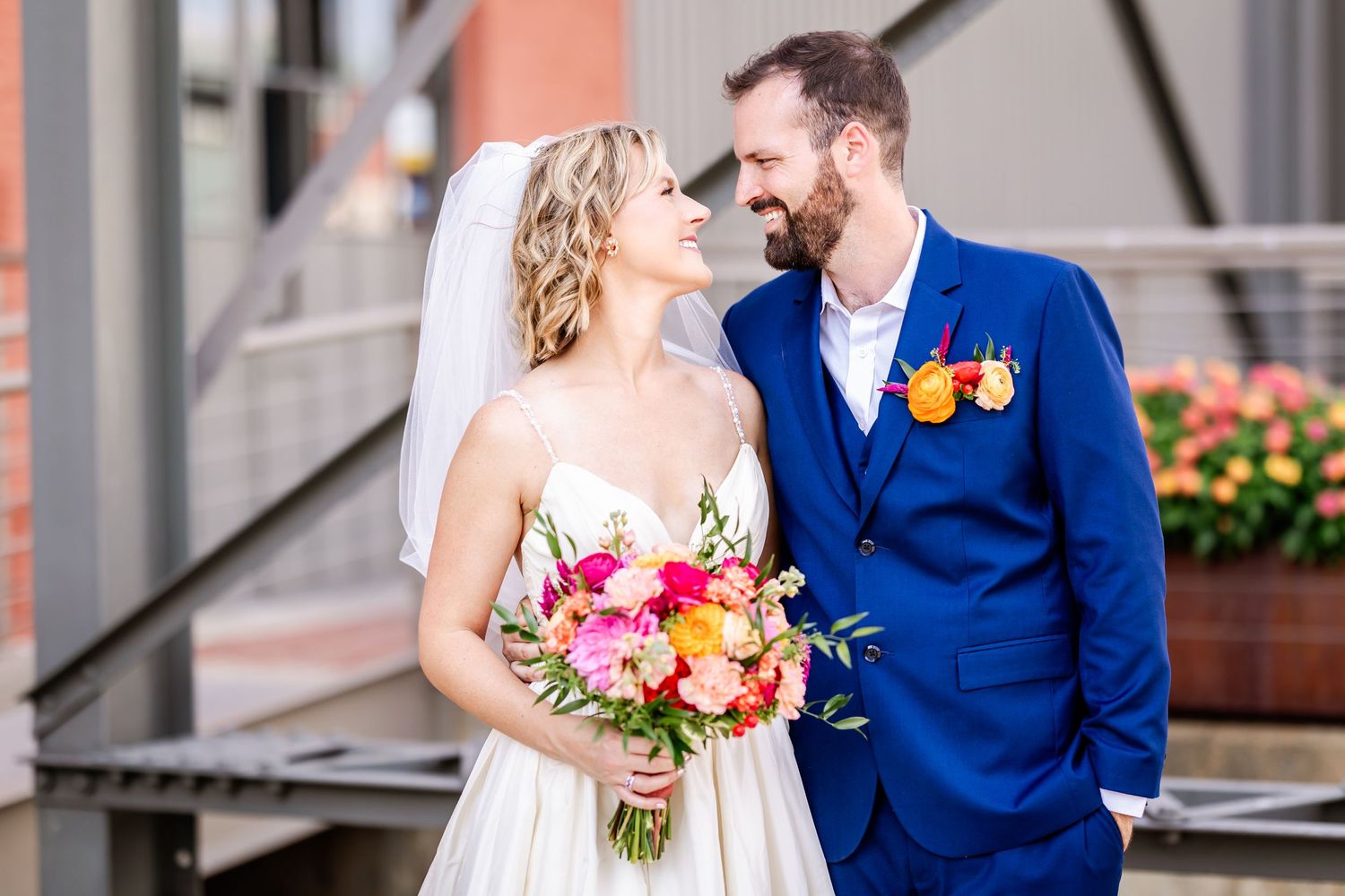 A joyful wedding portrait with bright florals against an urban backdrop.