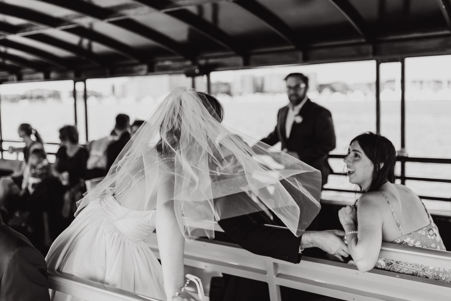 Wedding couple and guests celebrate on a covered boat deck in black and white.