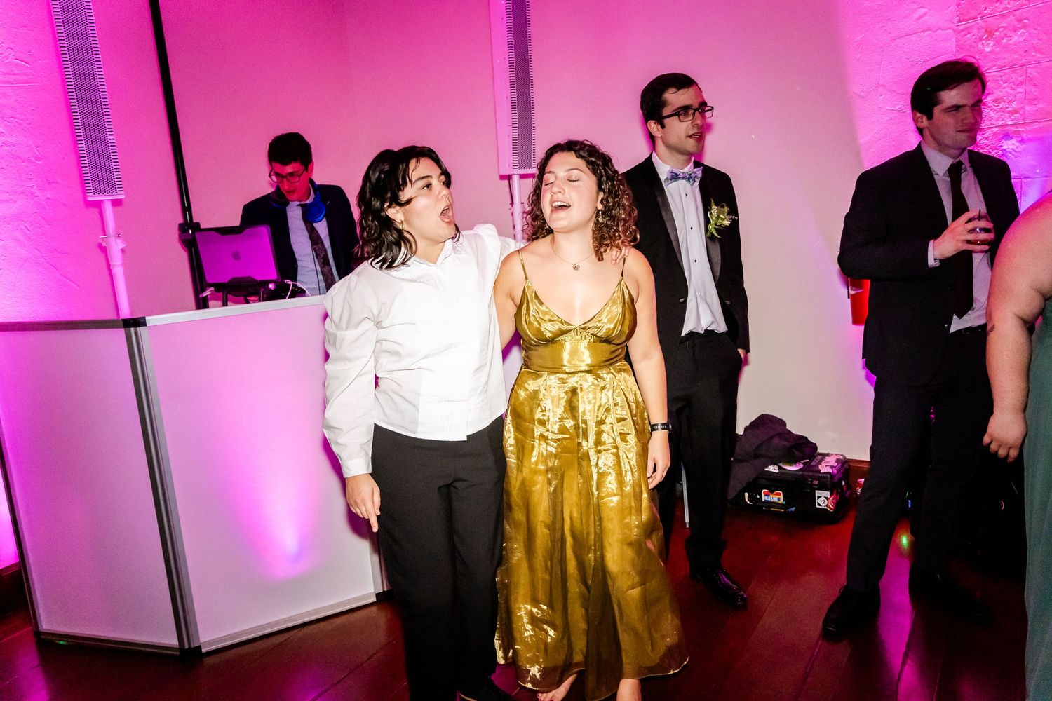 Wedding reception party with guests dancing under pink and purple lighting.