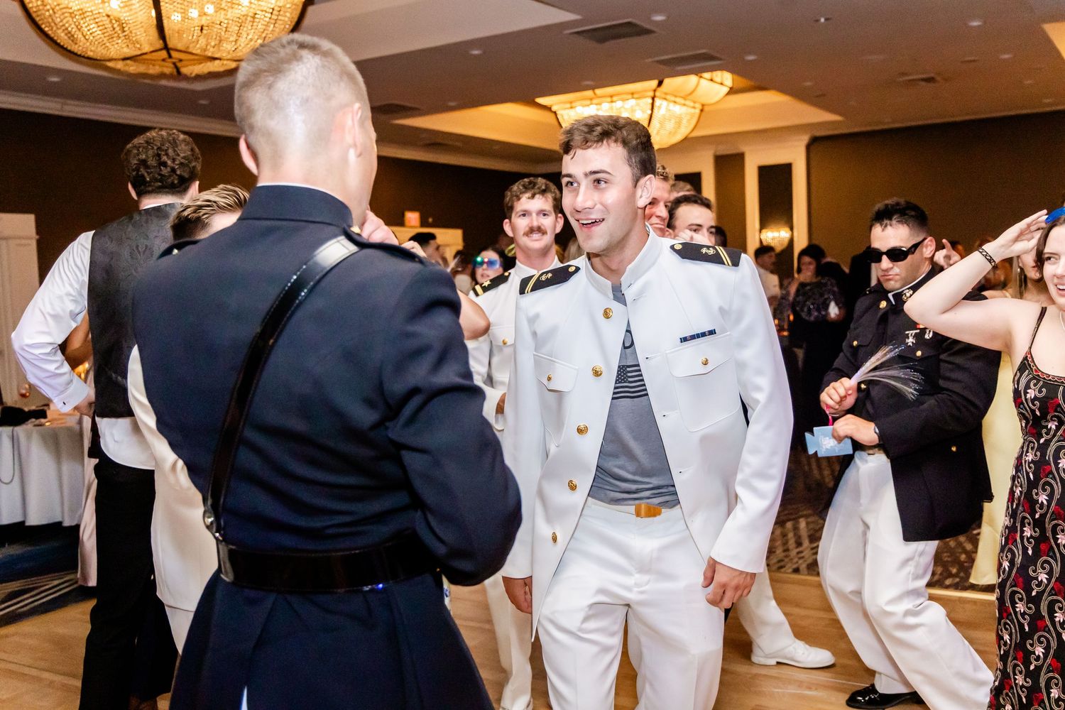 Wedding celebration with guests dancing and mingling under warm ballroom lighting.