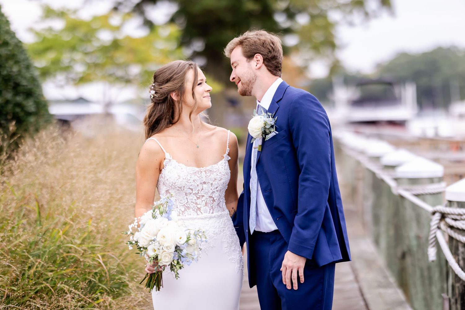 Newlyweds sharing a joyful moment together on a dock near boats and water.