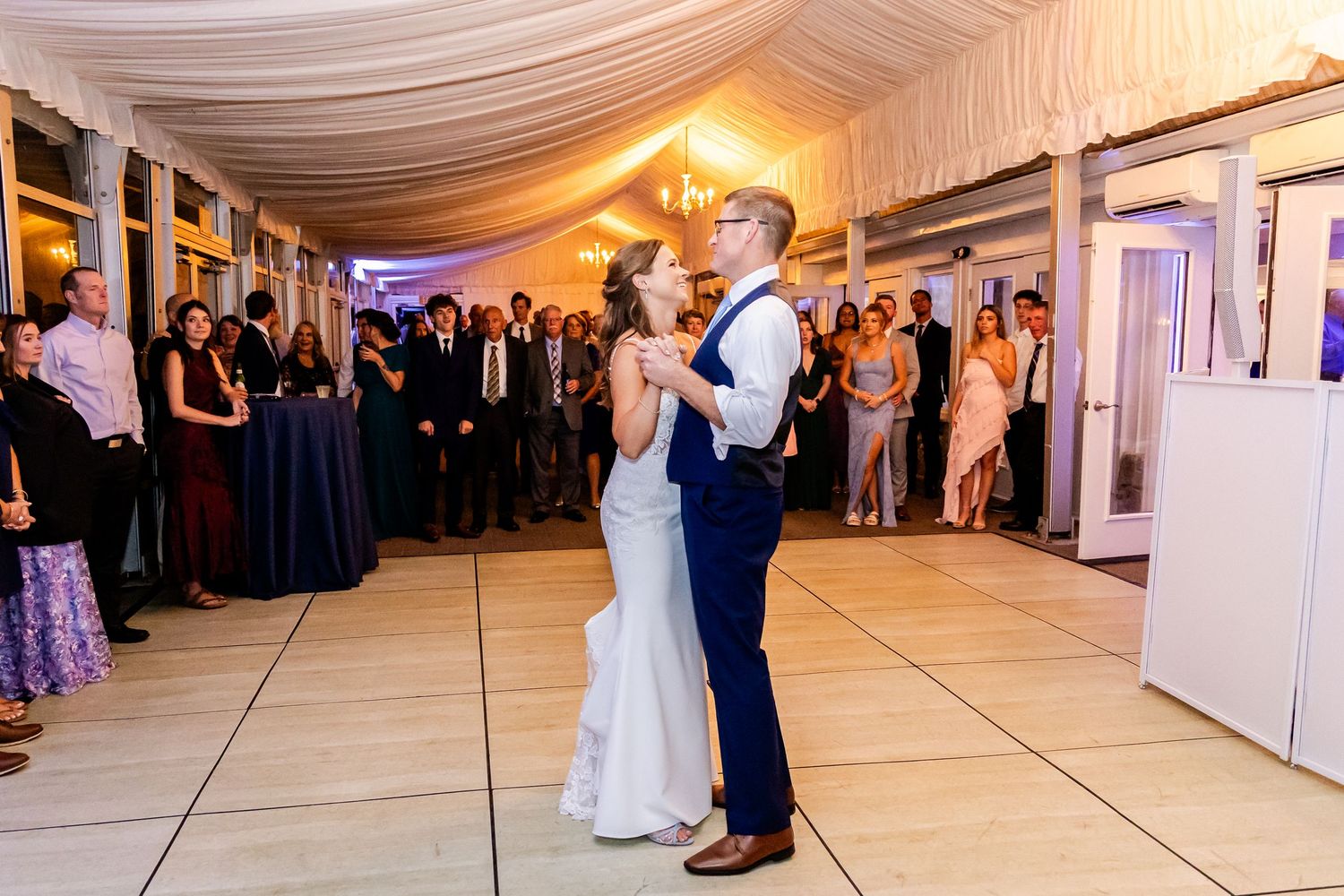 Wedding reception dance floor with draped ceiling and ambient lighting.