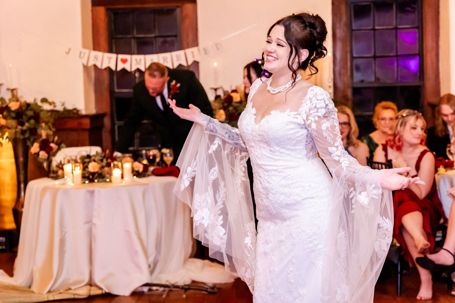 Wedding celebration in an elegant venue with exposed wooden beams and chandeliers.
