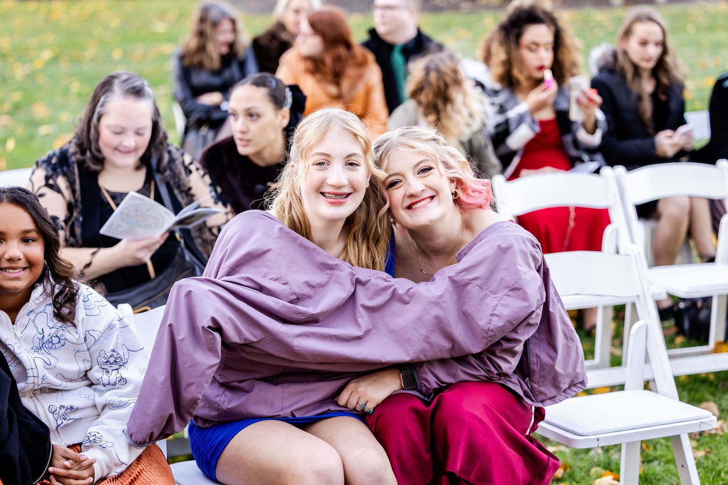 Wedding guests smiling and laughing together while seated outdoors.