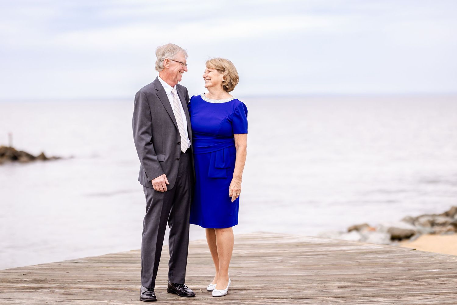 A couple walking along a scenic boardwalk during a formal occasion.