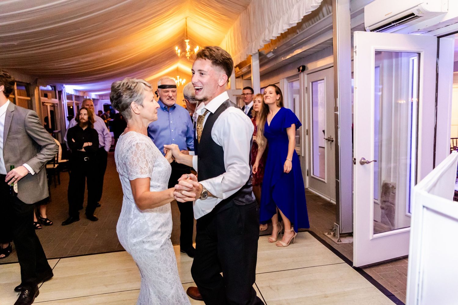 Wedding reception dancing and celebrations inside a decorated white tent venue.