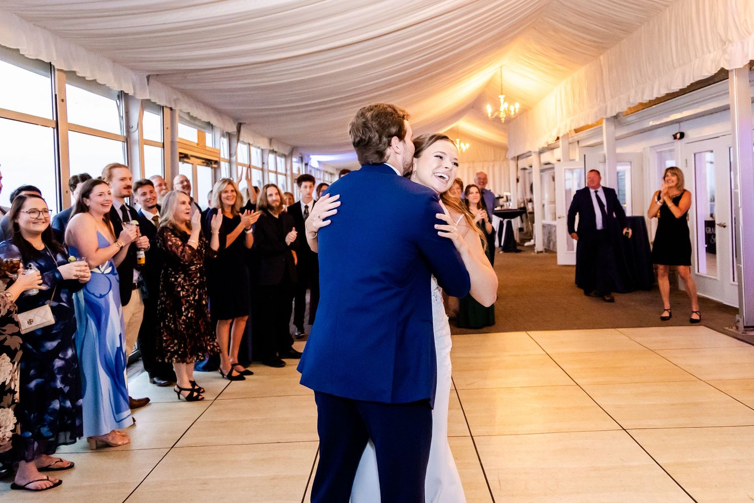 Wedding reception panorama showing guests dancing and celebrating in an elegant white tent venue.